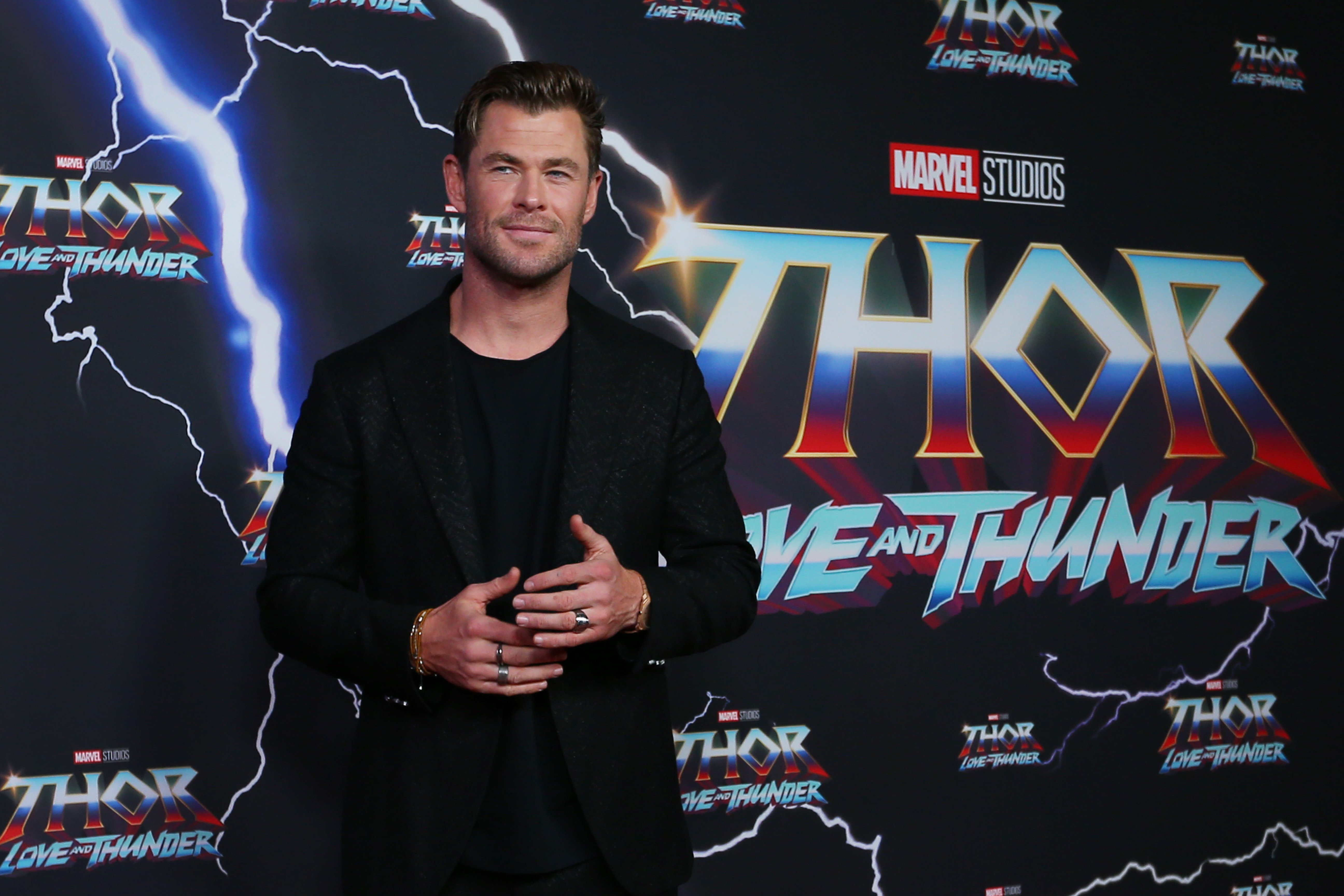 Chris Hemsworth, who stars in 'Thor: Love and Thunder,' which isn't getting great reviews on Rotten Tomatoes, wears a black suit over a black shirt.
