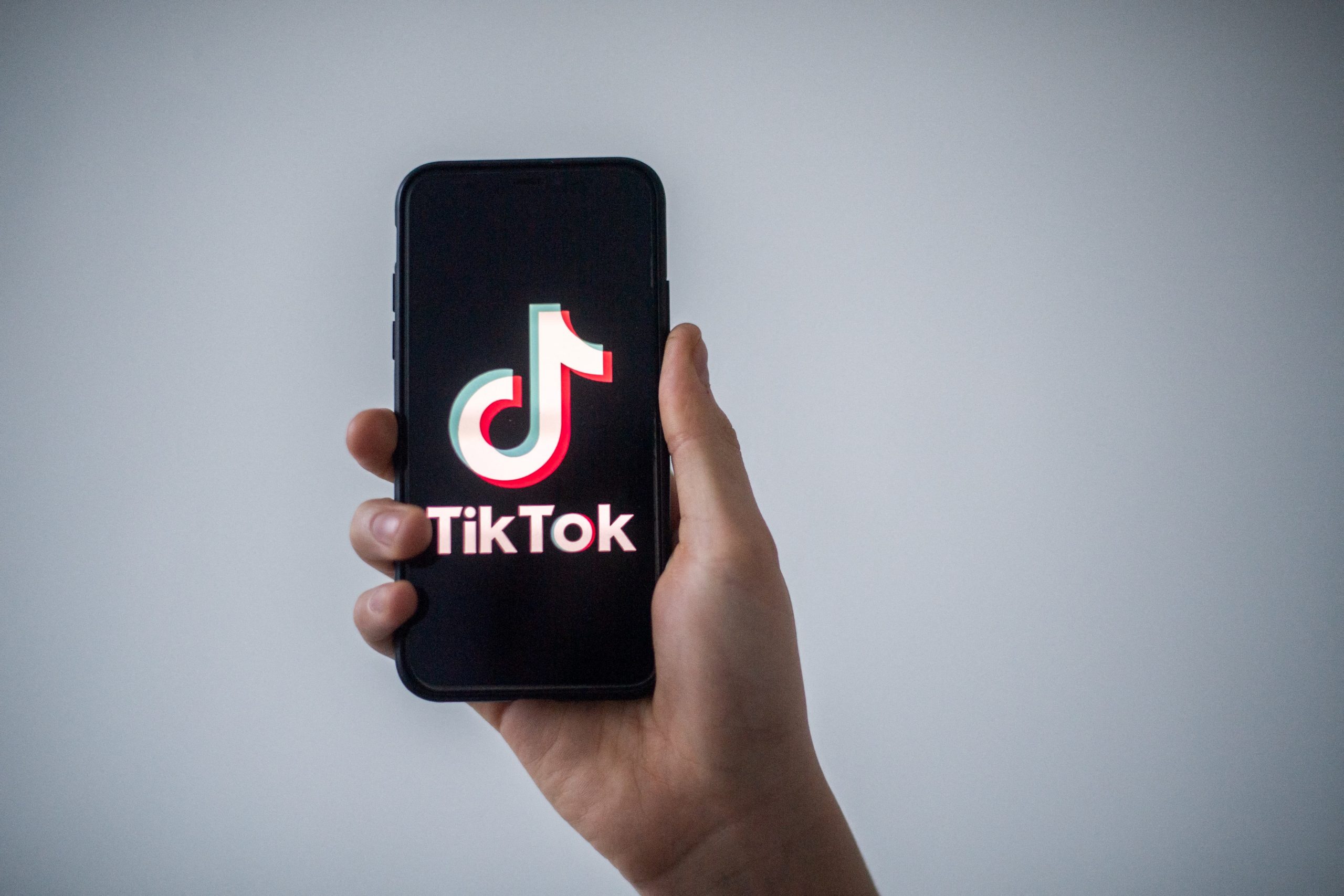 A smartphone with the Tik Tok logo displayed. A viral TikTok house has everyone talking