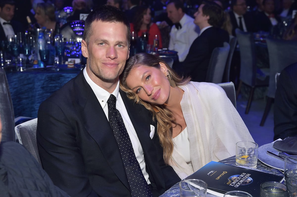 Tom Brady and Gisele Bundchen sit together at an event.
