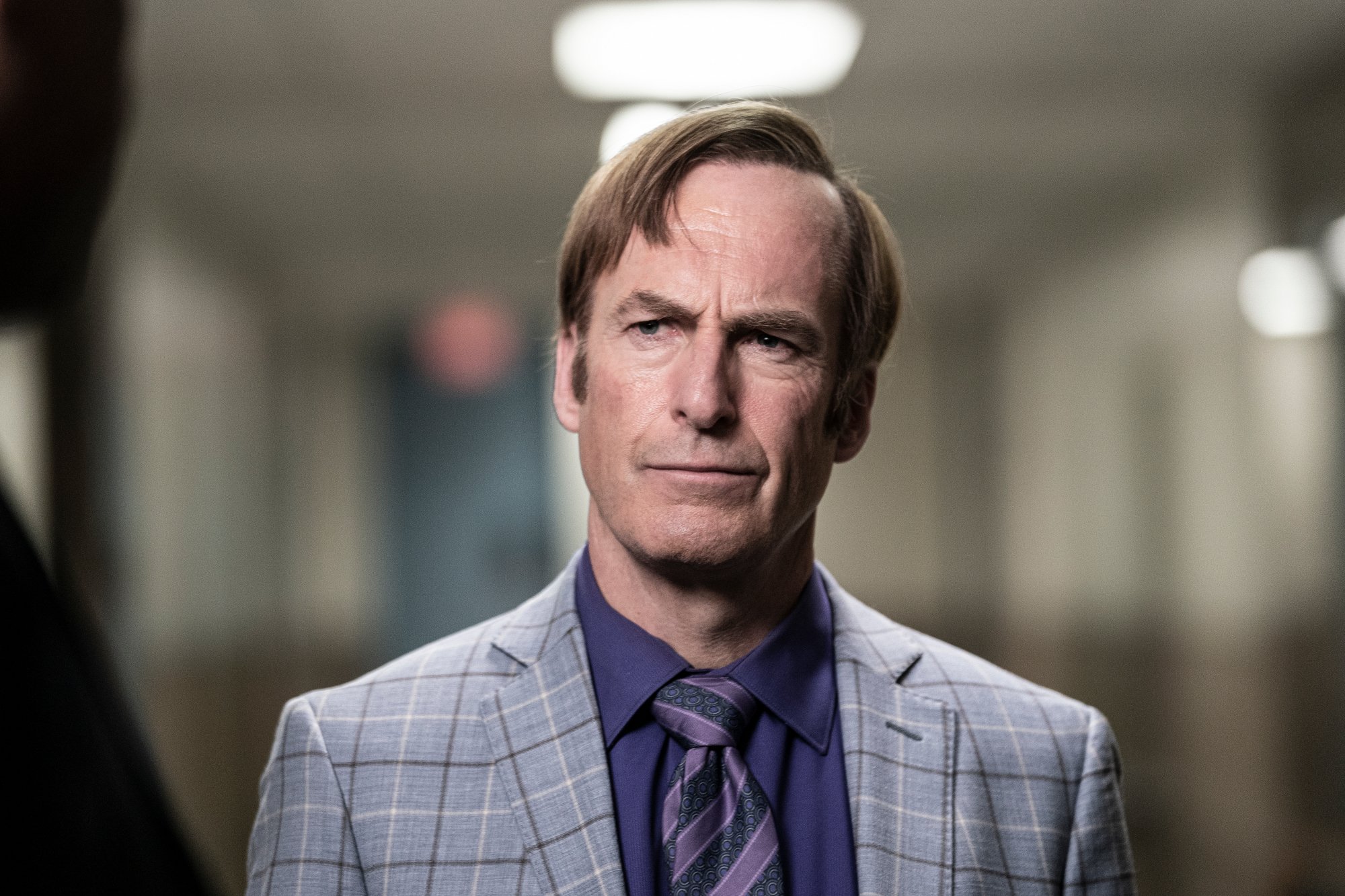 Bob Odenkirk as Saul Goodman in 'Better Call Saul' Season 6 for our article about when the premiere will air tonight. The image shows him wearing a blue shirt and gray suit and wearing a perplexed expression.
