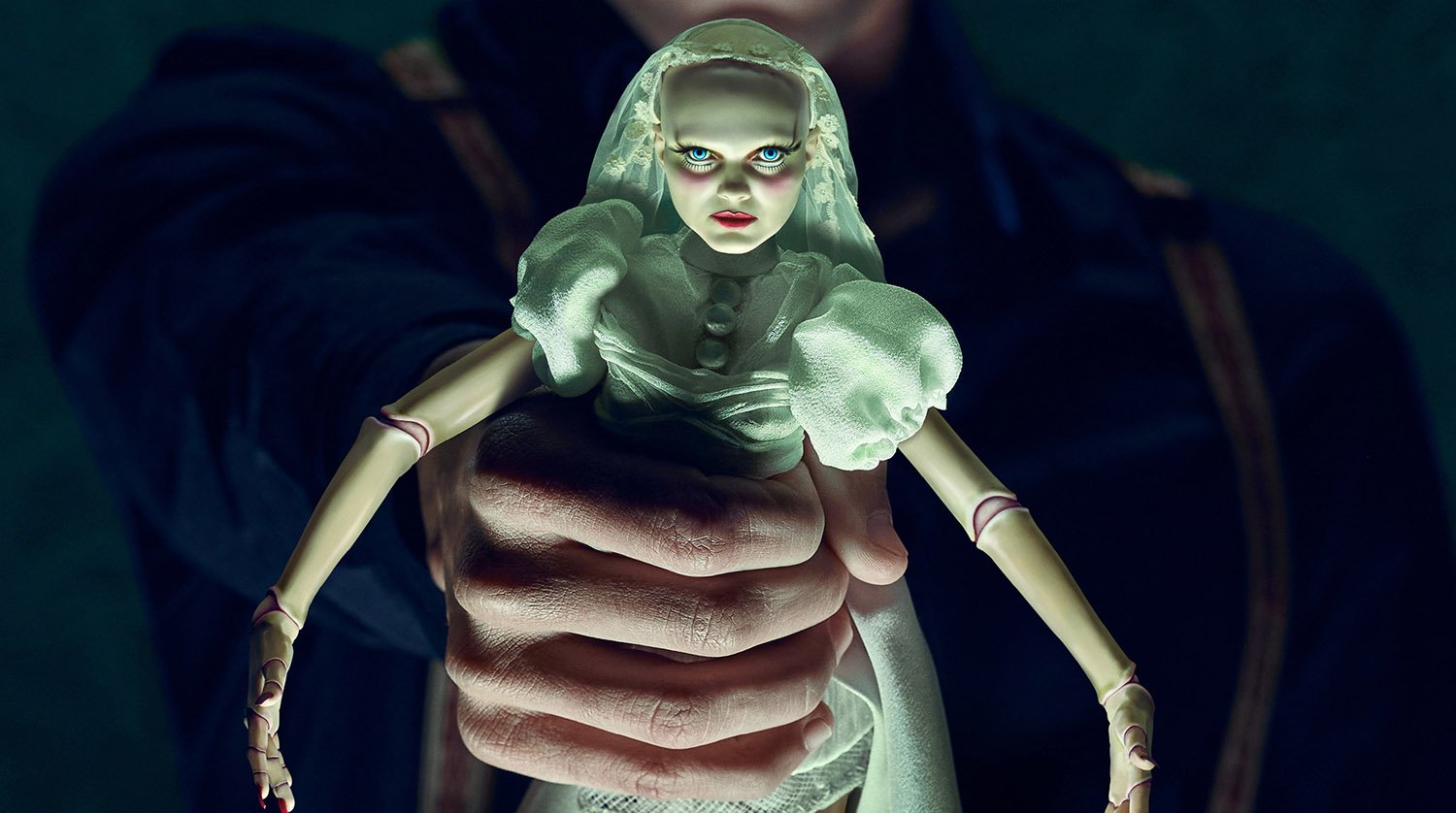 A man holds a doll in a wedding dress in key art for American Horror Stories Season 2, which has a star-studded cast.