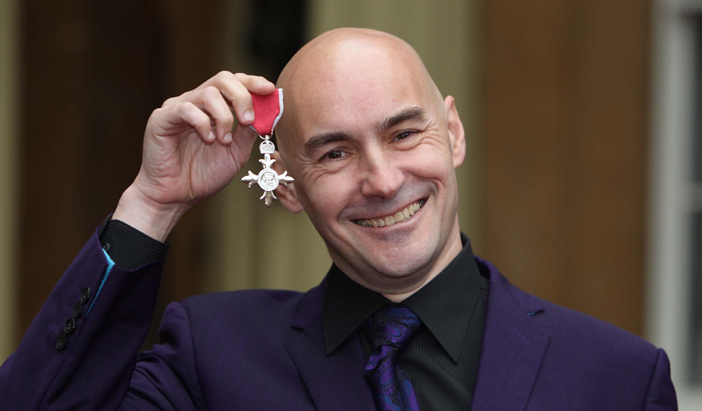 Grant Morrison holding a medal