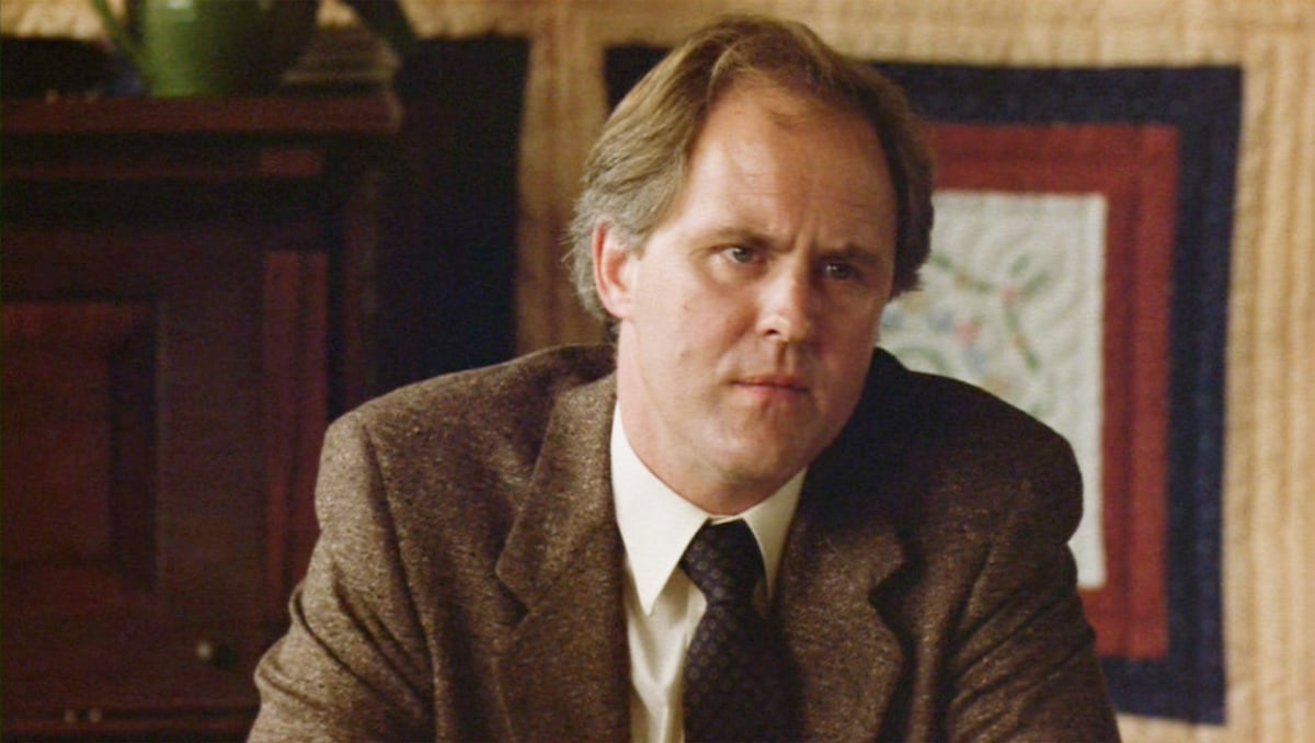 John Lithgow as Reverend Shaw Moore in 'Footloose' in a suit looking serious