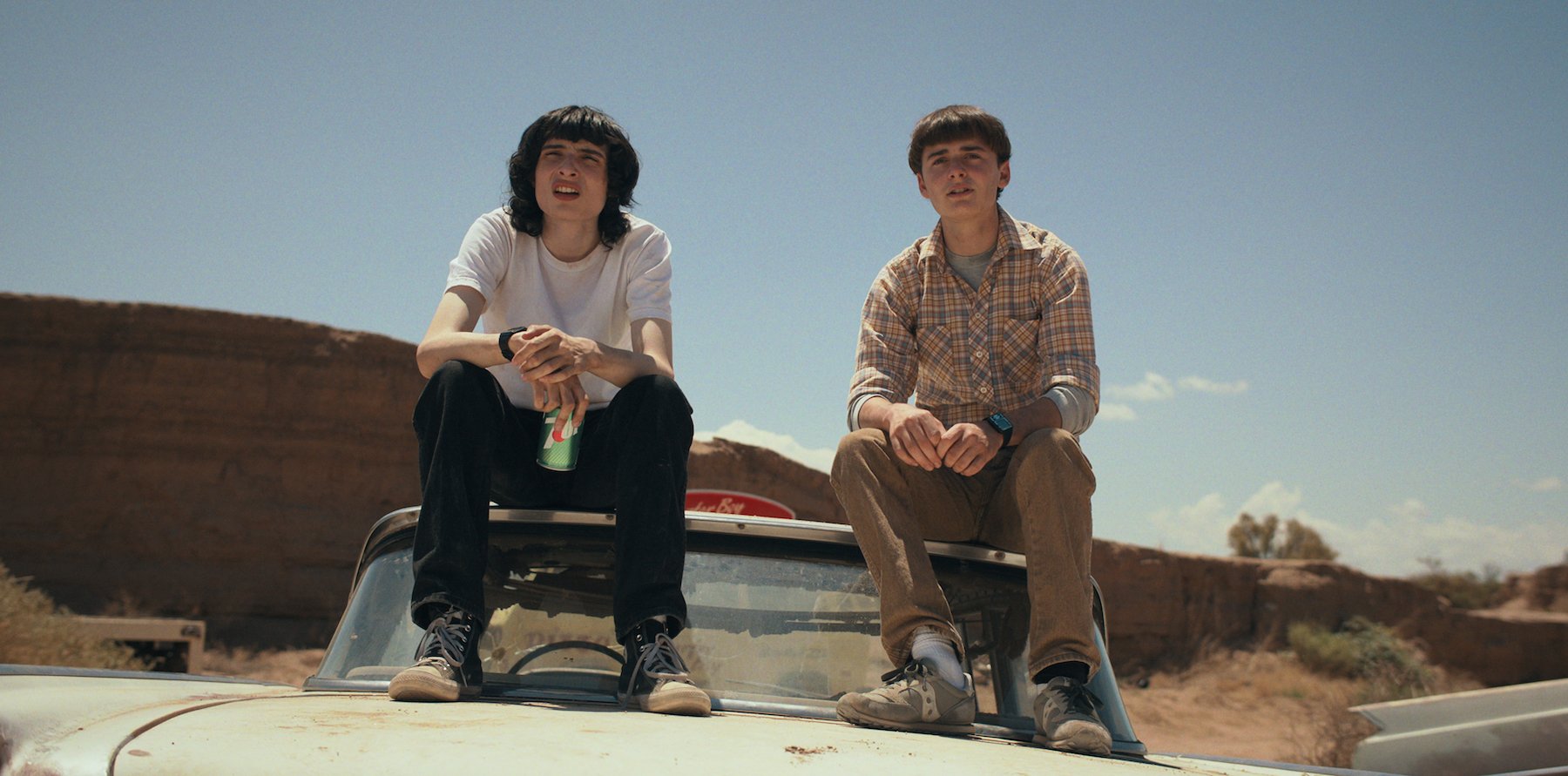 Mike (Finn Wolfhard) and Will (Noah Schnapp), who presents Mike with a painting this season, sit on top of a car in 'Stranger Things 4'