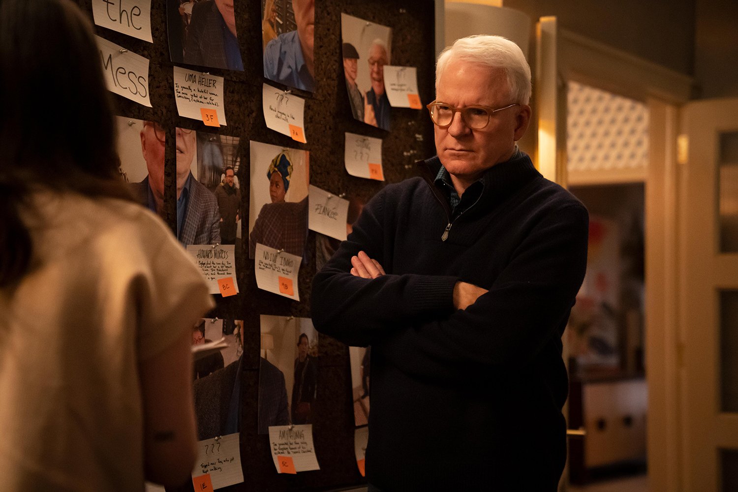Steve Martin as Charles in Only Murders in the Building Season 1, standing next to an investigation board filled with loose ends