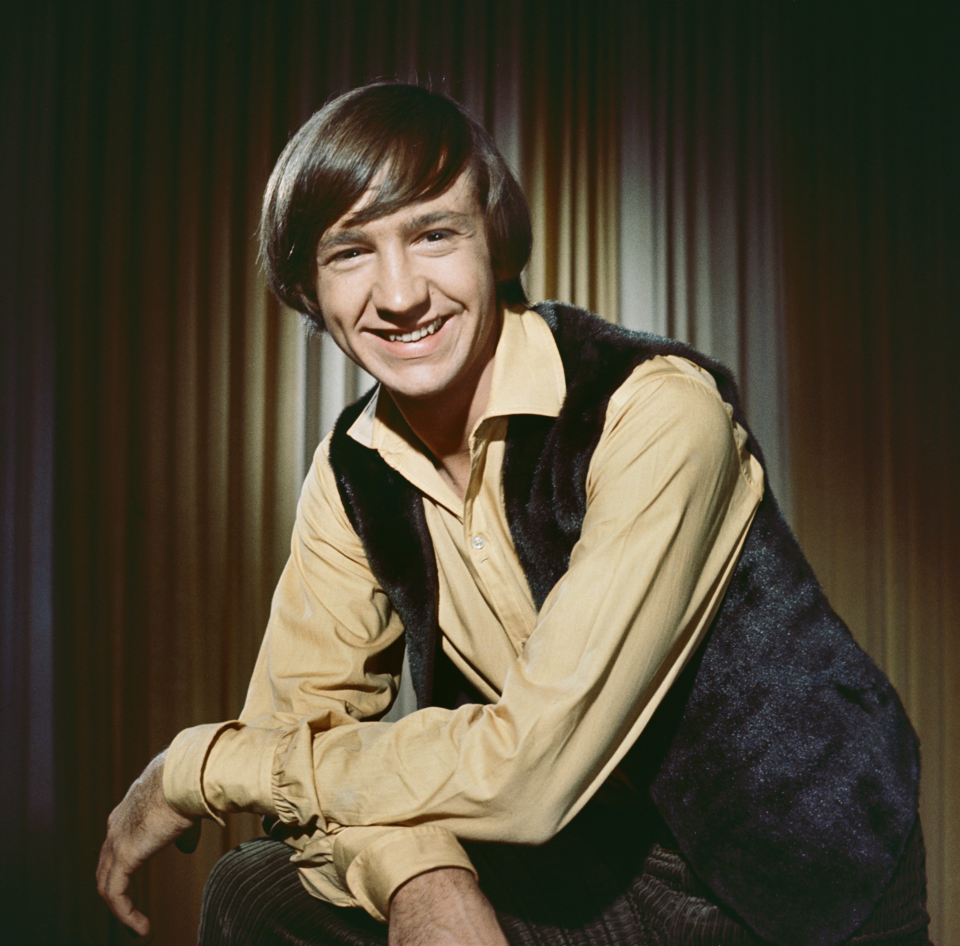 The Monkees' Peter Tork in front of a curtain