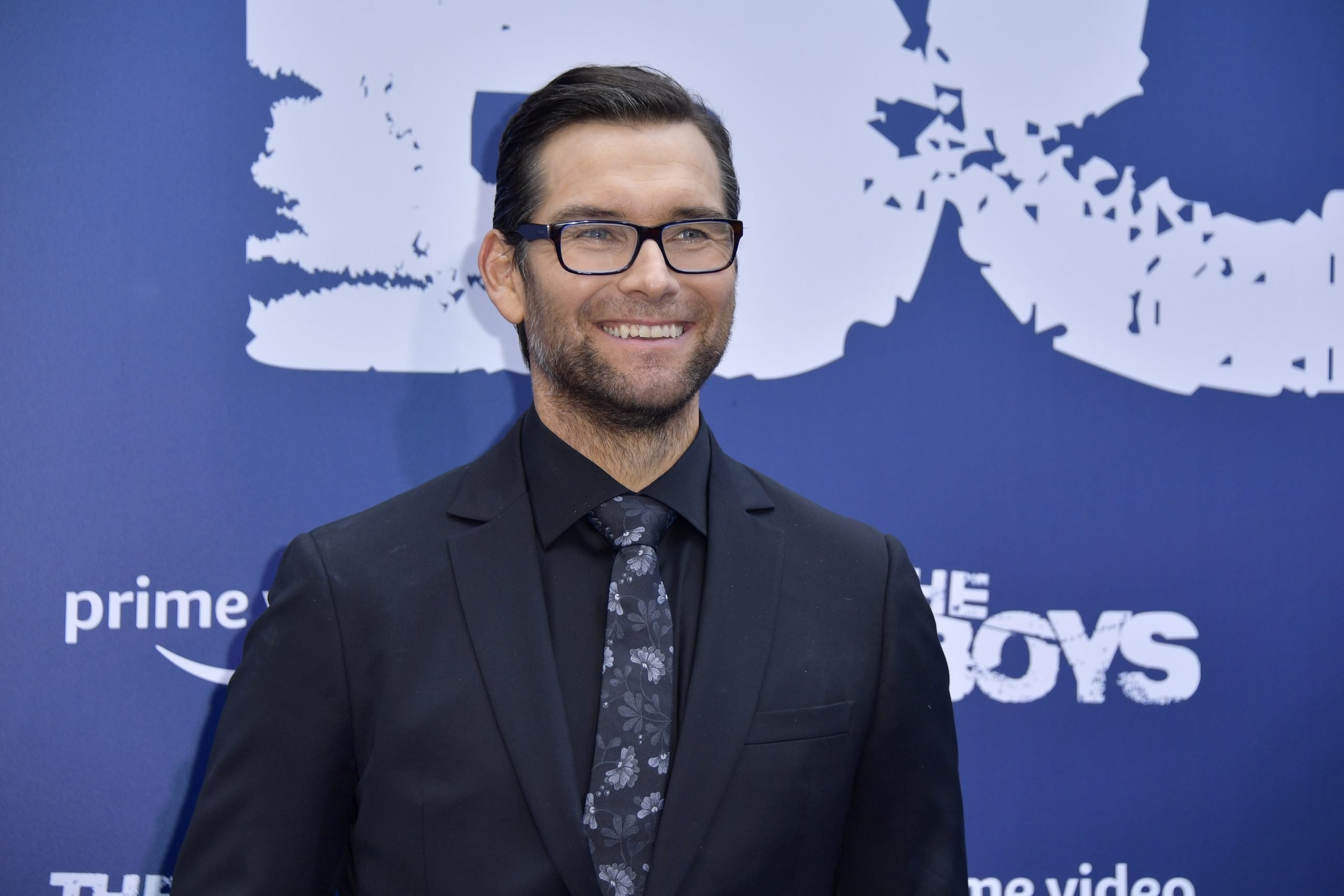 'The Boys' cast member Antony Starr smiling in front of a blue backdrop