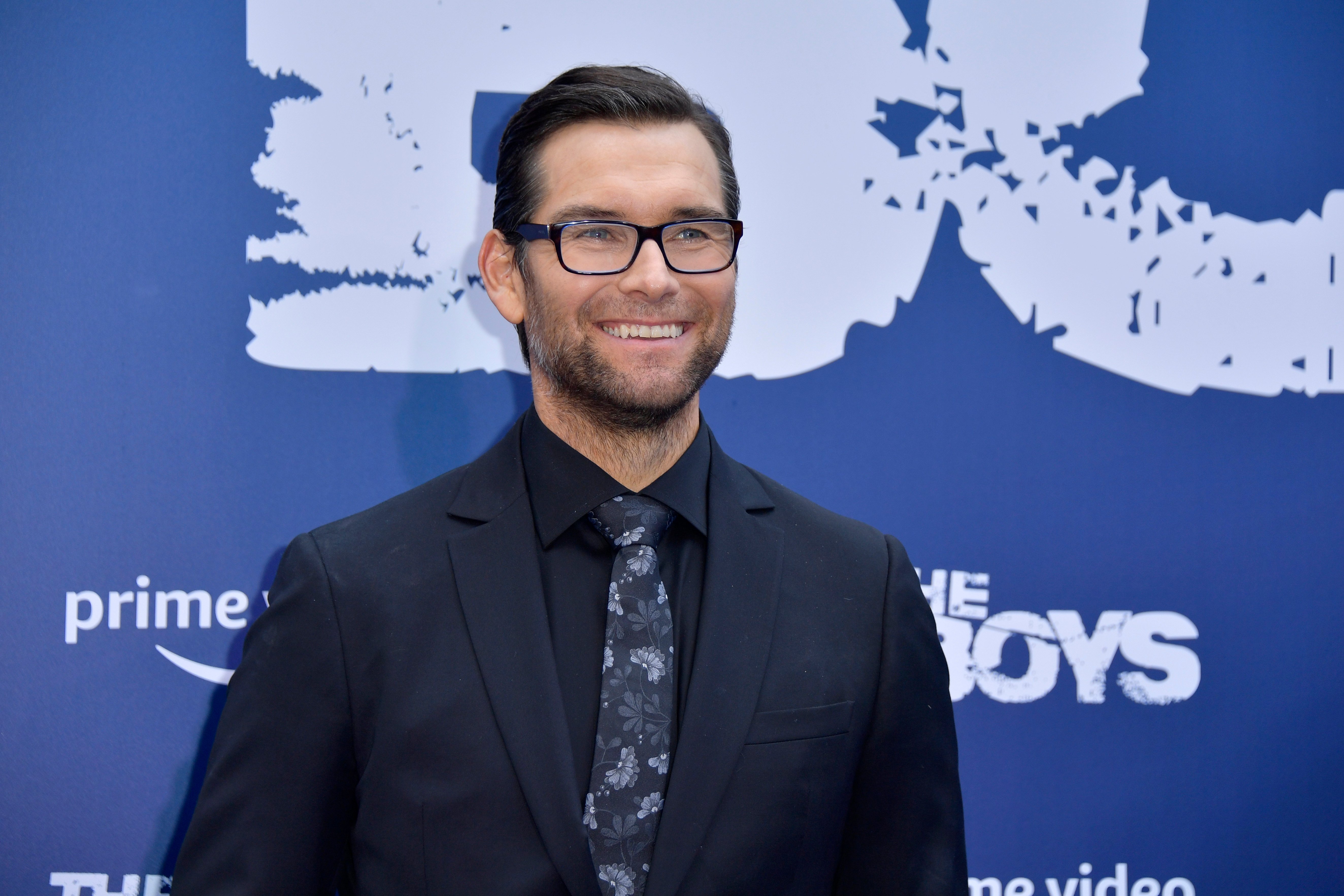 The Boys cast member Antony Starr smiling in front of a blue backdrop