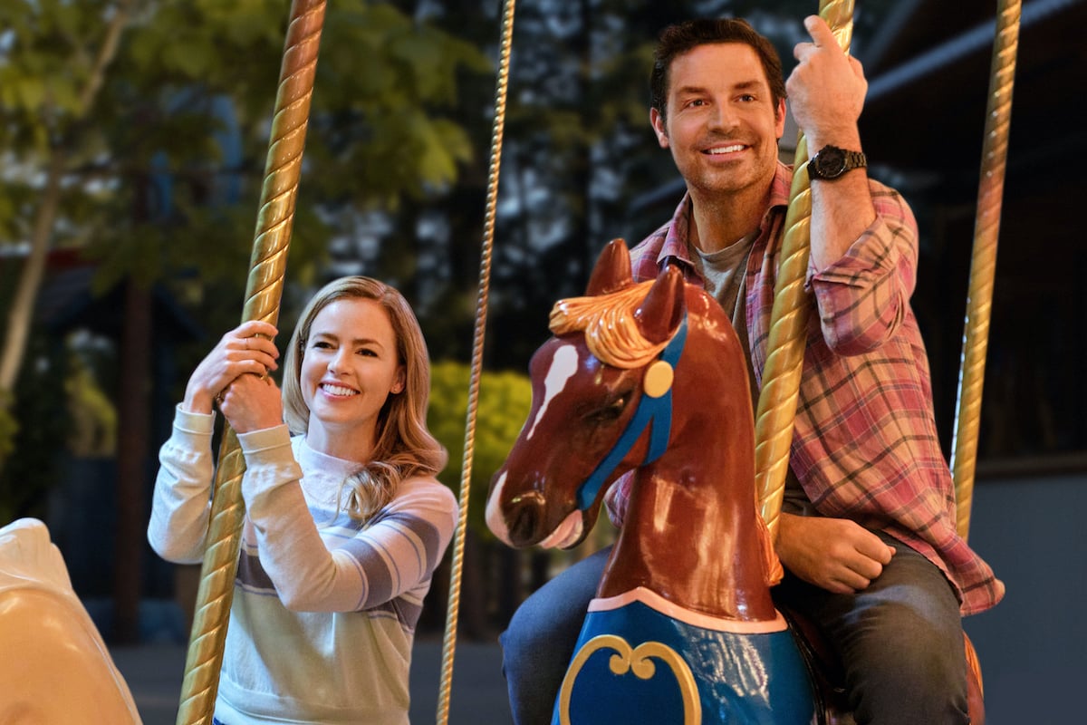 Amanda Schull and Brennan Elliott riding a merry-go-round in the Hallmark Movie 'Marry Go Round'