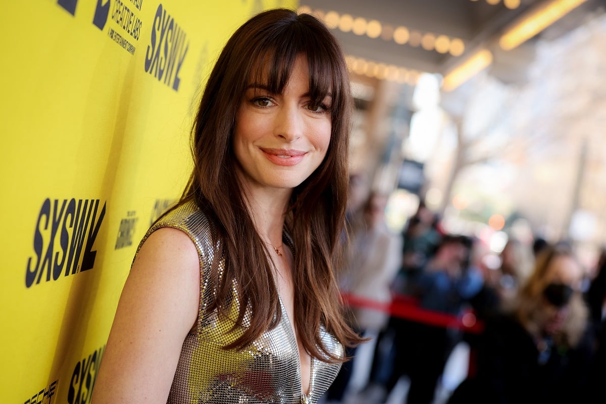 Anne Hathaway smiling while wearing a gold dress.