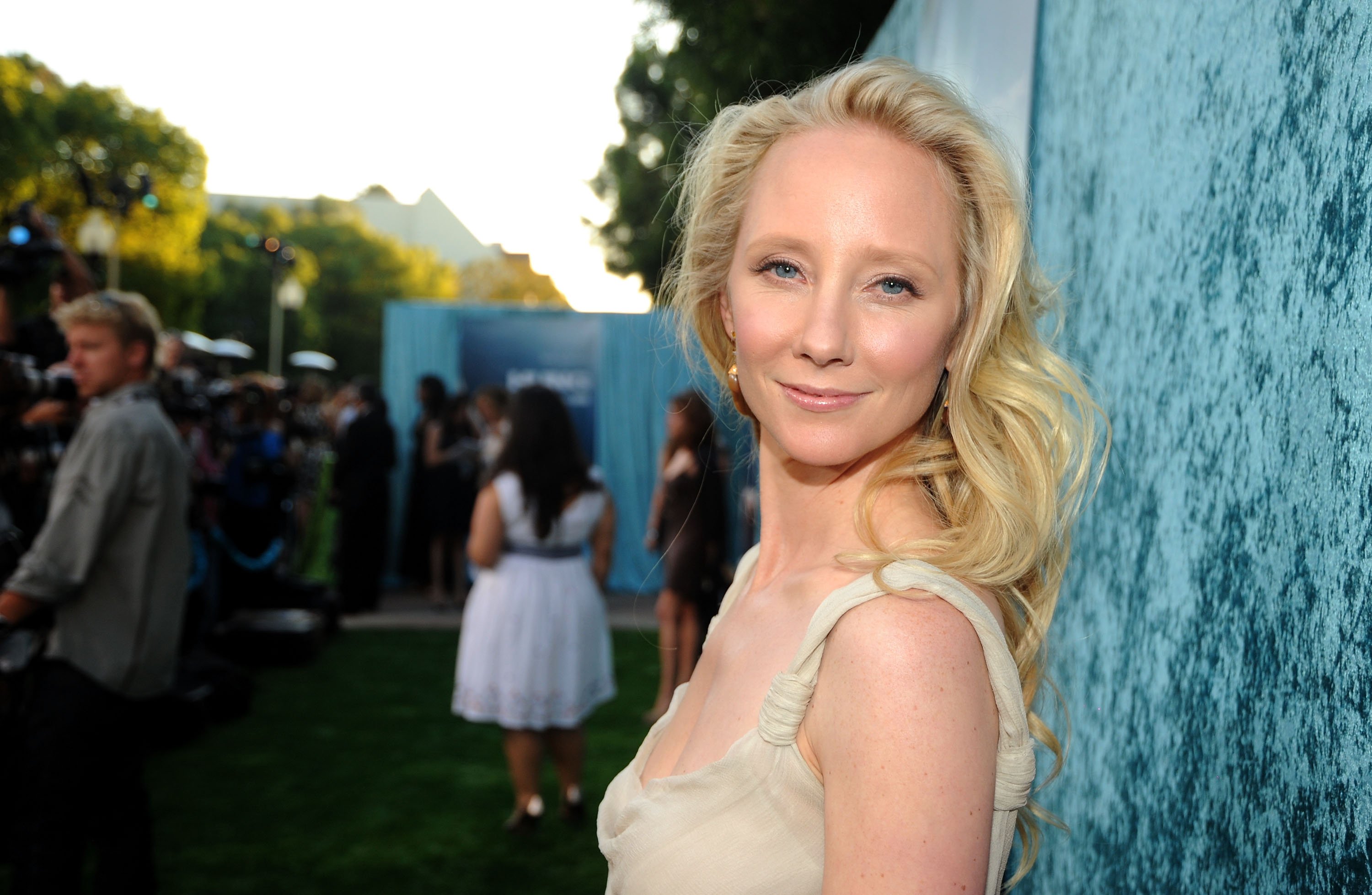 Anne Heche poses in a cream colored dress at a media event.