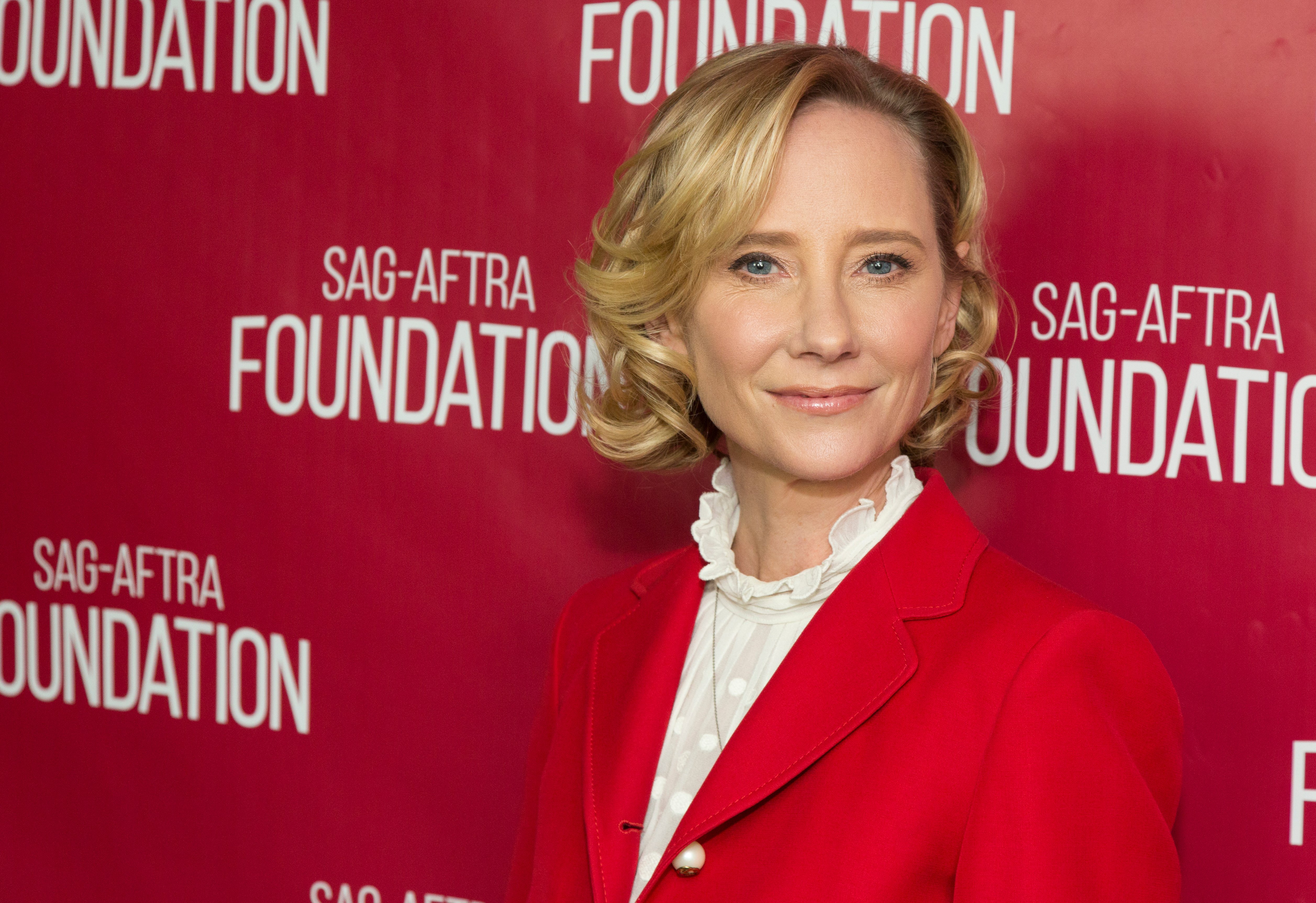 Anne Heche poses in a red suit.
