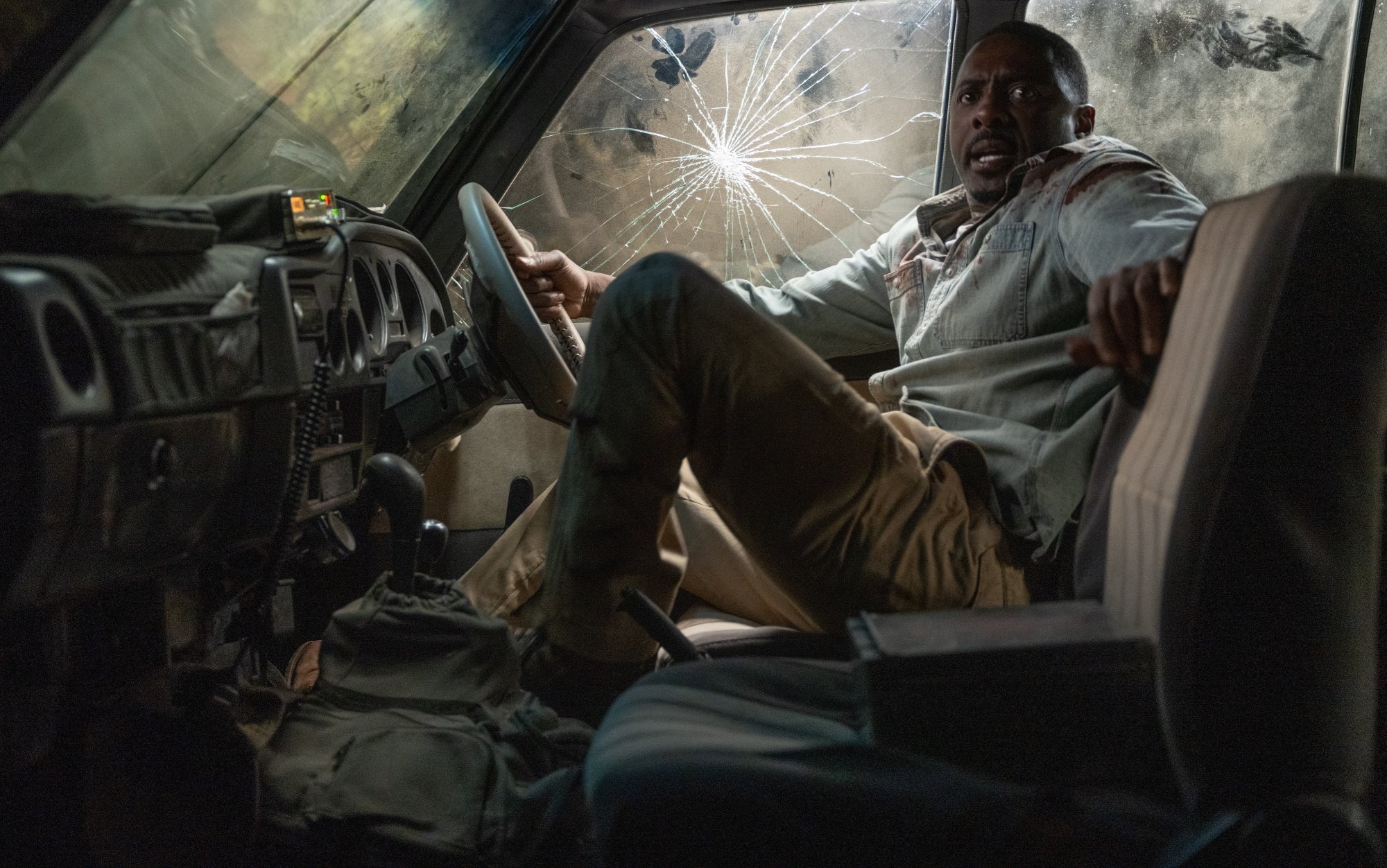 'Beast' movie starring Idris Elba as Dr. Nate Daniels. looking scared in a car with cracked window holding onto the wheel