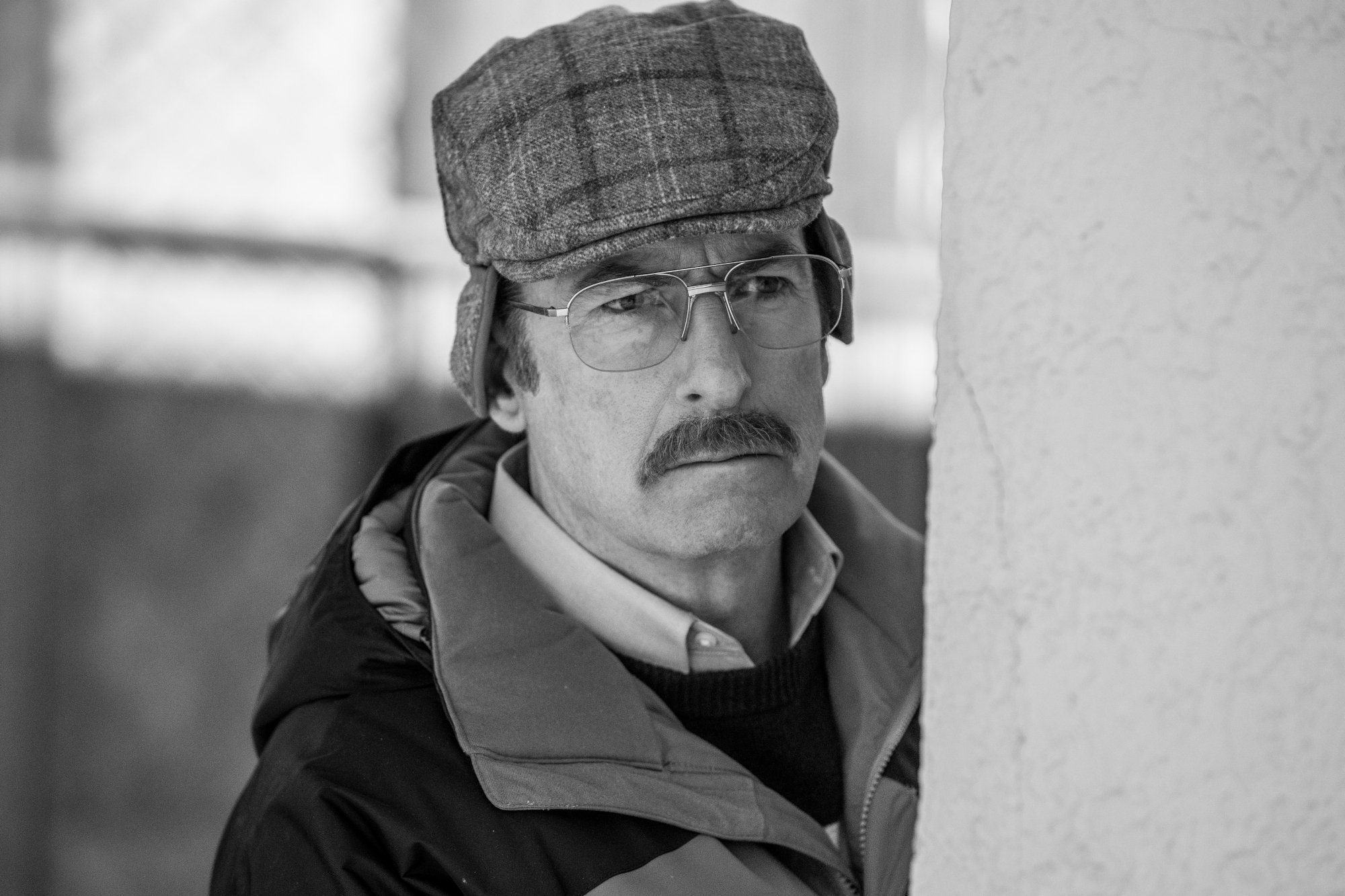 Bob Odenkirk in 'Better Call Saul' Season 6 Episode 13, the series finale. He's wearing glasses and a hat and peeking out from behind a wall