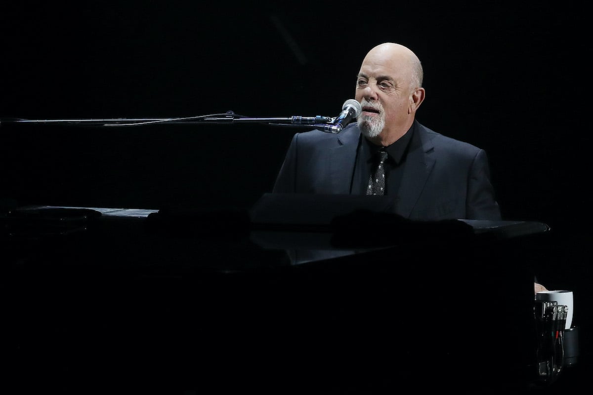 Billy Joel sitting at a piano performing on stage