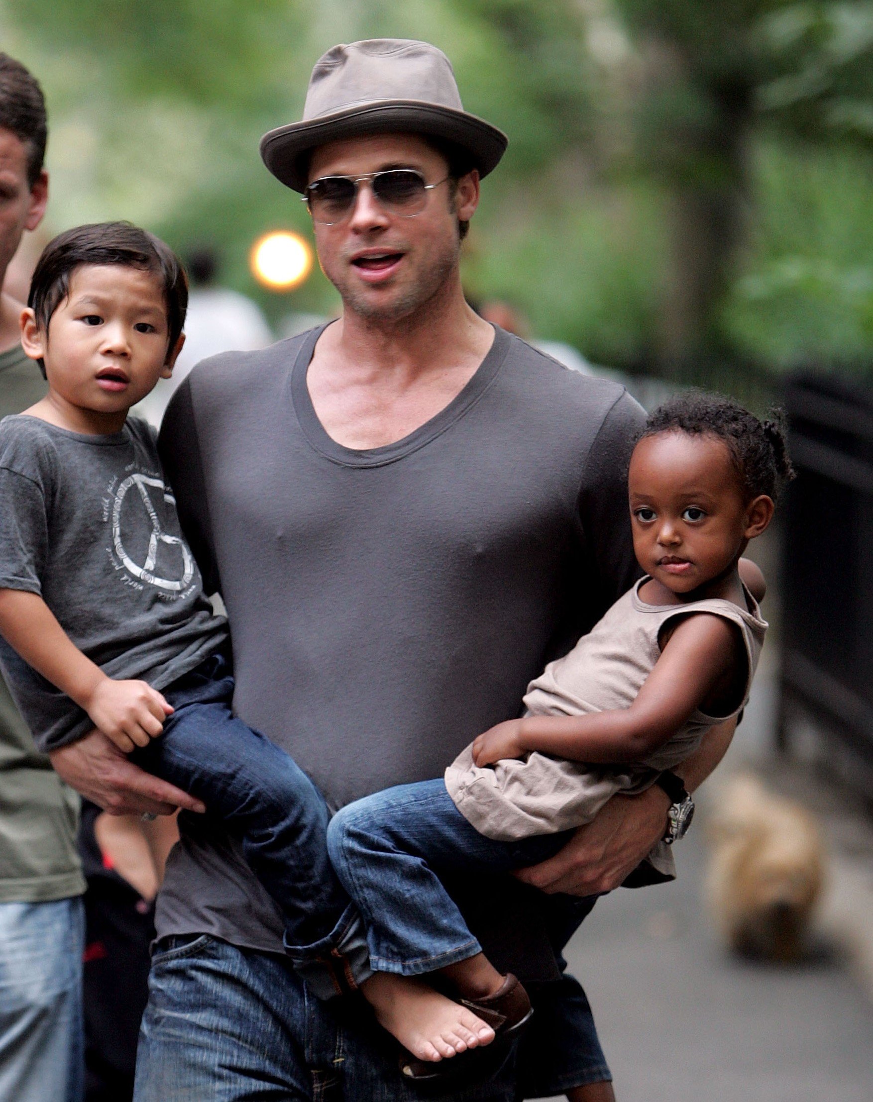 Brad Pitt holding a young Pax on his one side and a young Zahara on the other