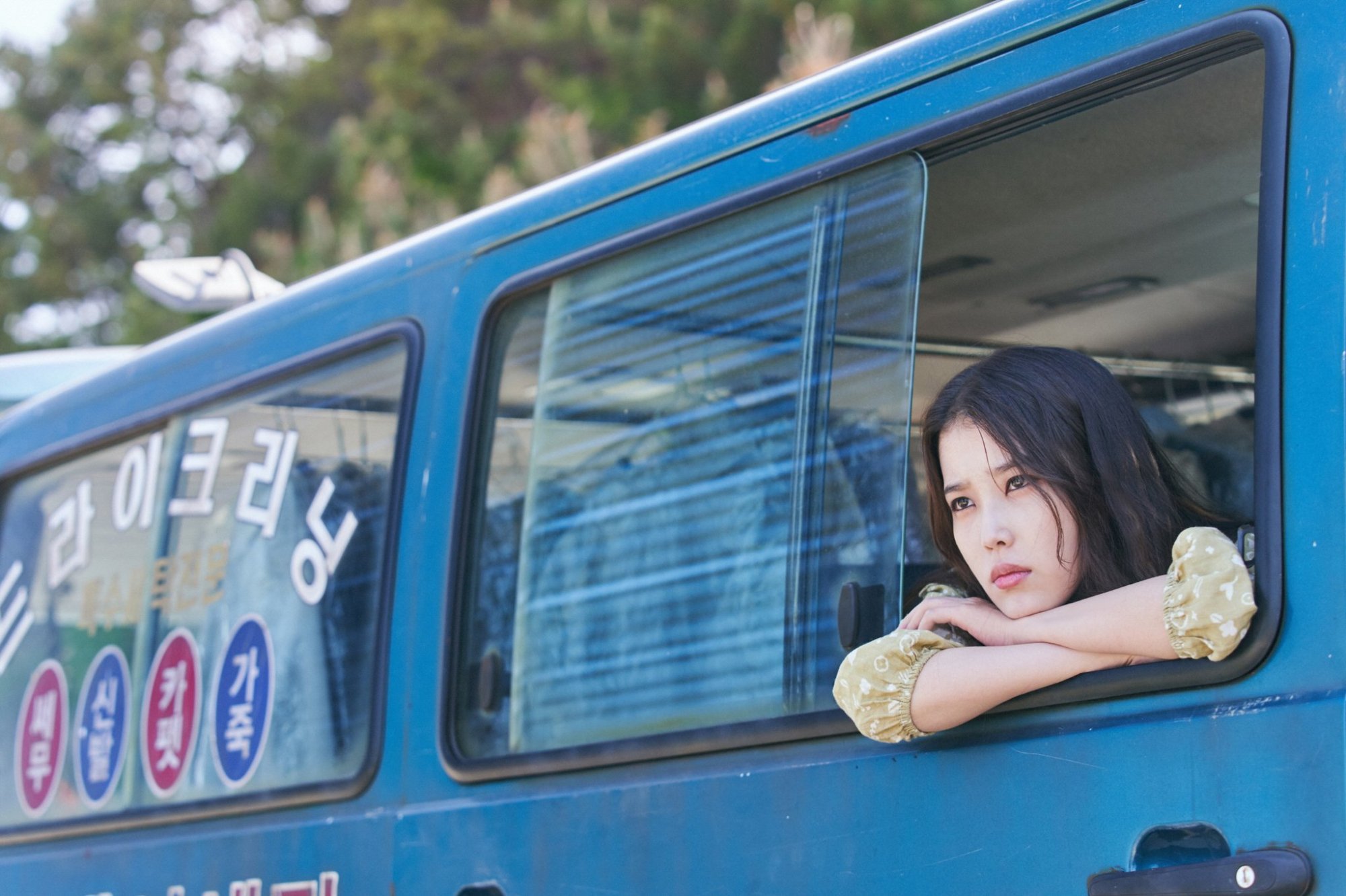 a young woman leans out a van window, gazing forlornly