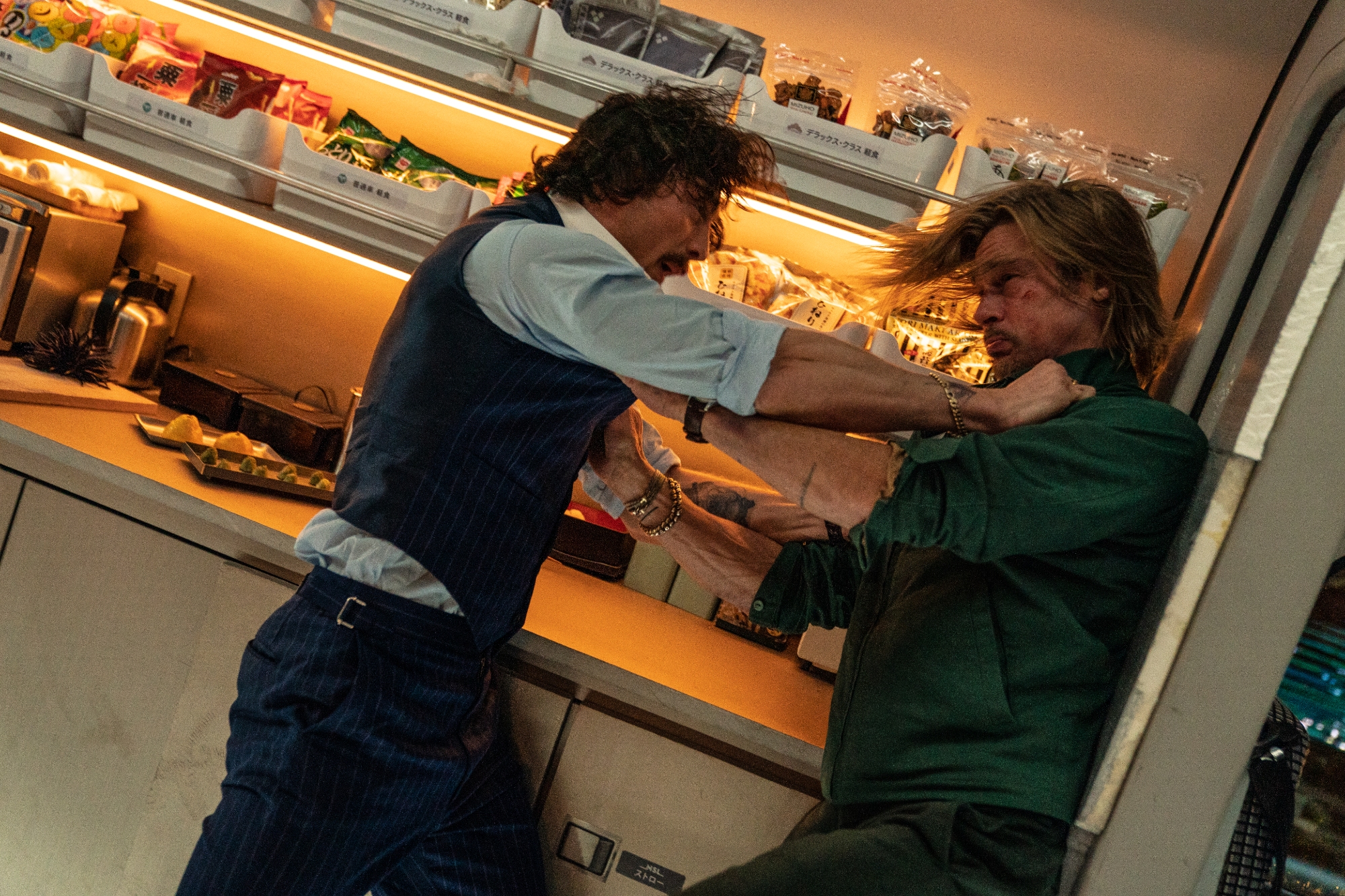 'Bullet Train' Aaron Taylor-Johnson as Tangerine and Brad Pitt as Ladybug fighting in front of a collection of the train snack counter