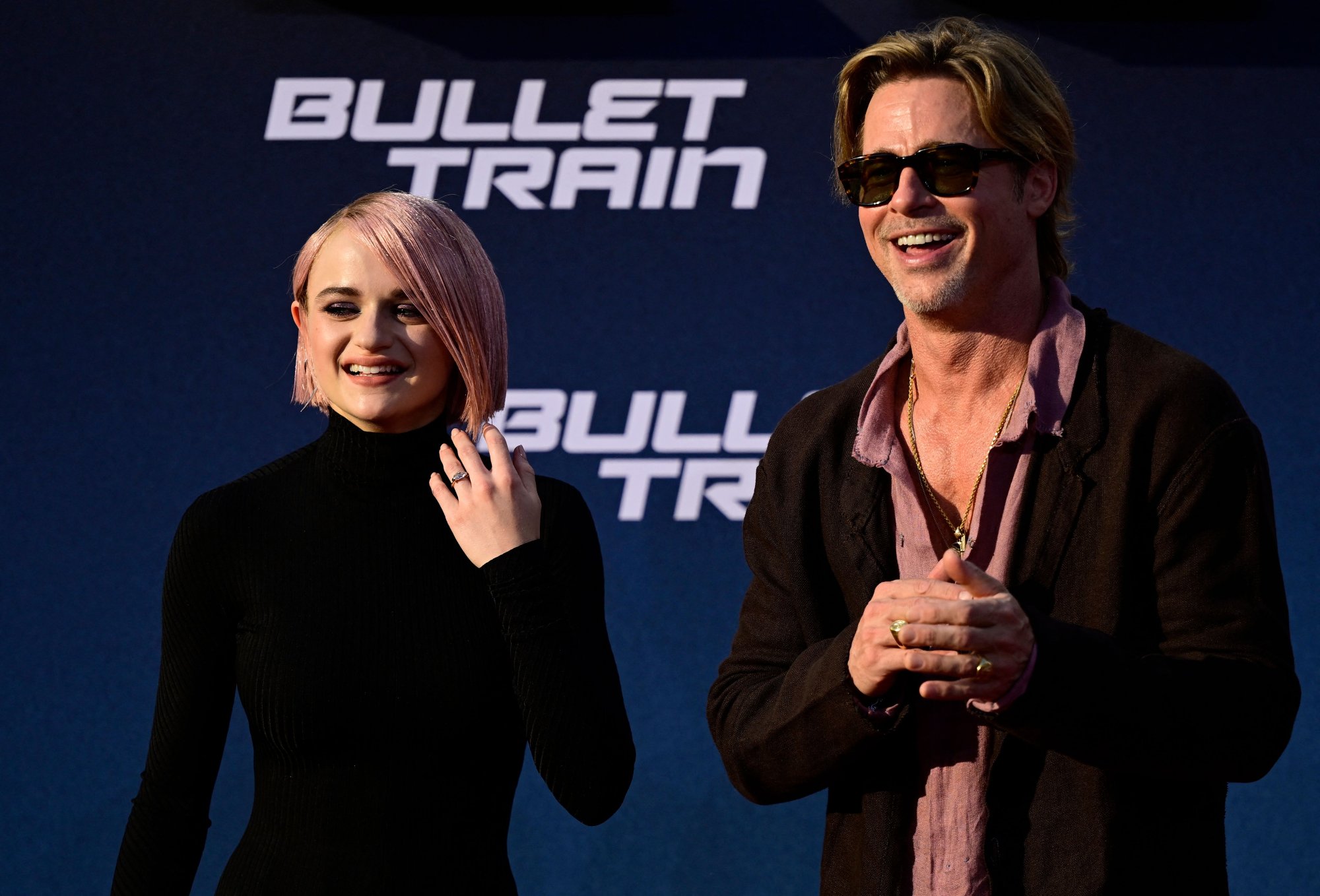 'Bullet Train' Joey King and Brad Pitt smiling in front of movie title font