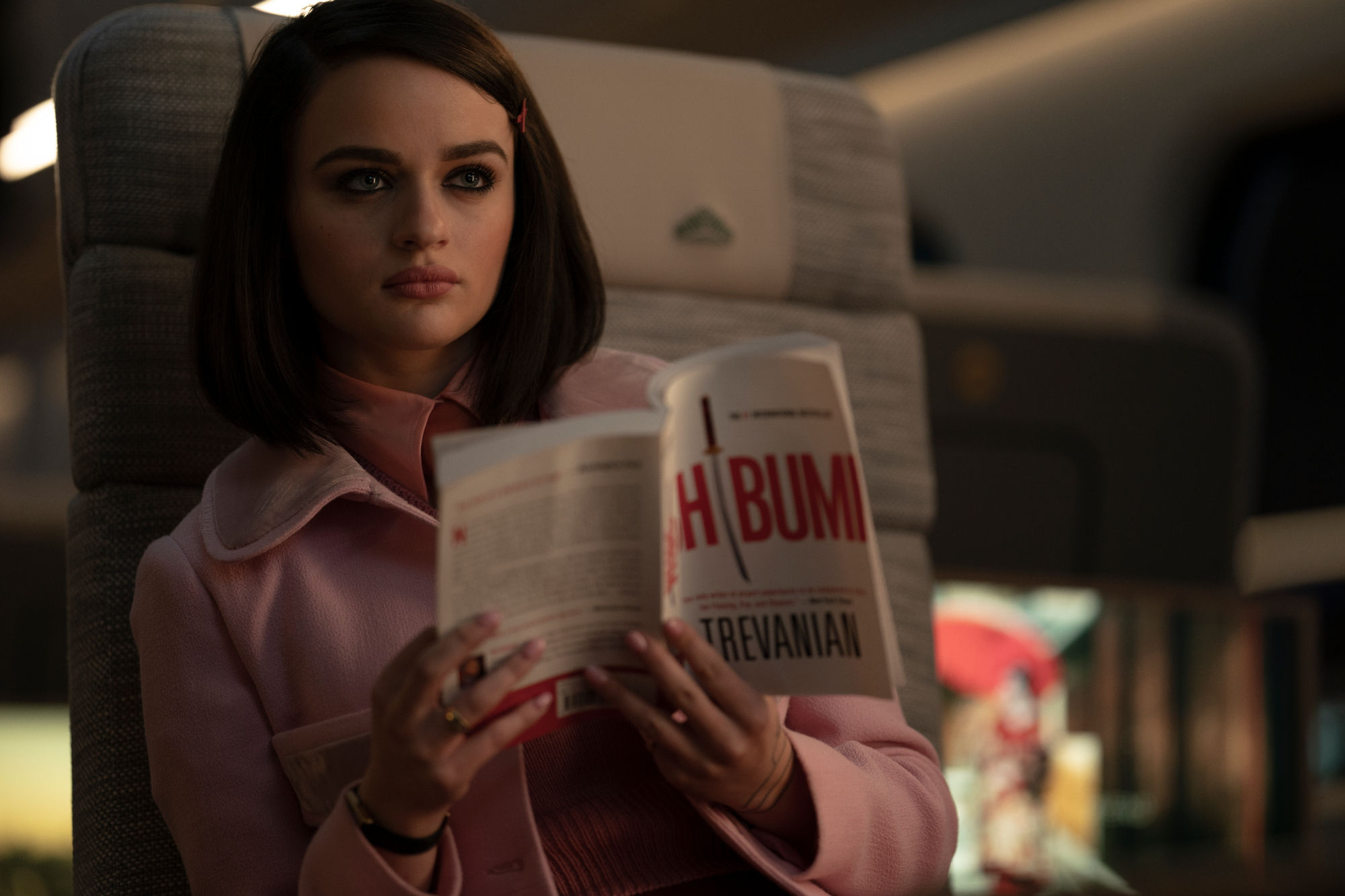 'Bullet Train' Joey King as The Prince reading a book, while wearing pink in a train seat