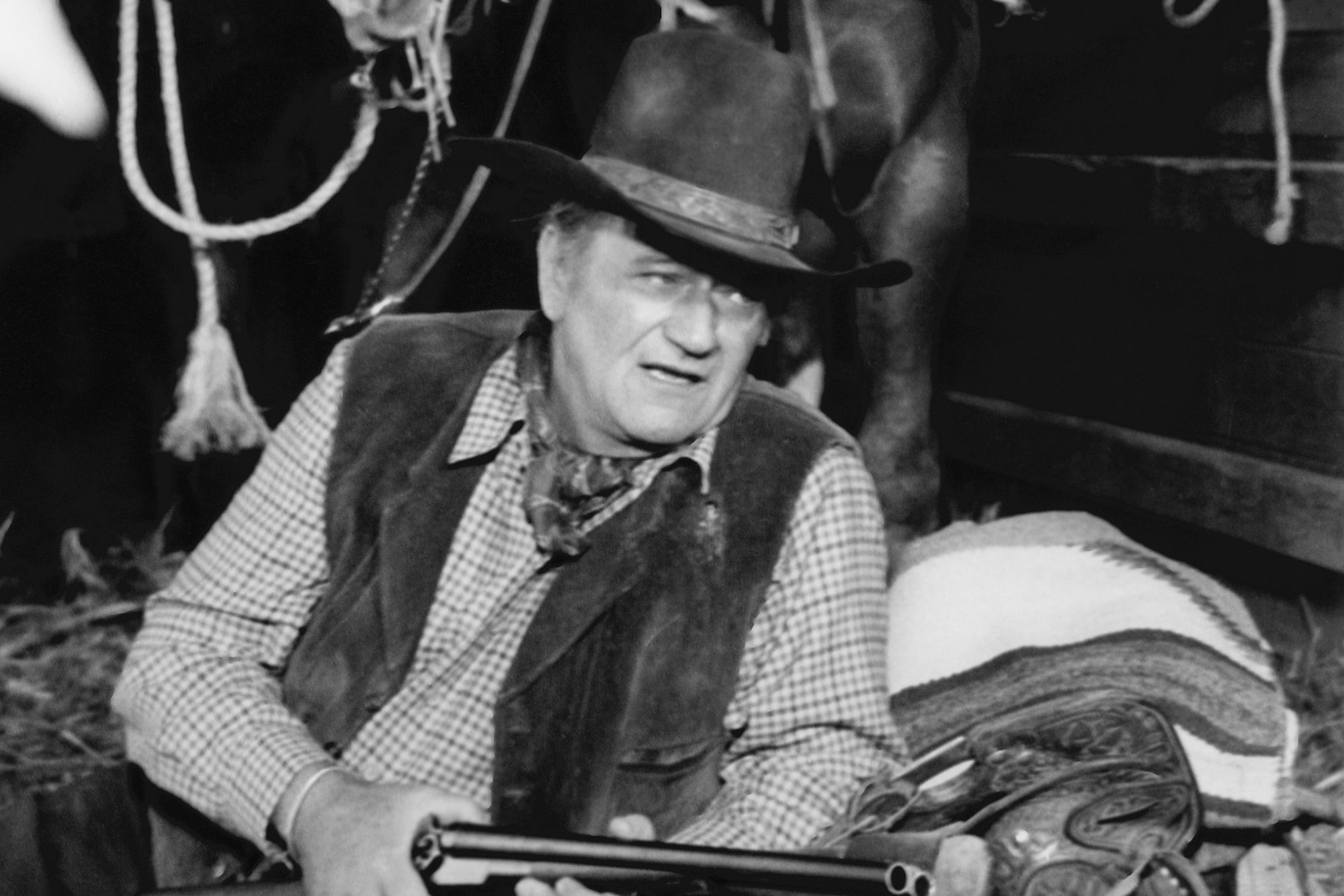 'Cahill U.S. Marshal' John Wayne as J.D. Cahill wearing his Western uniform and holding a gun in front of a horse.