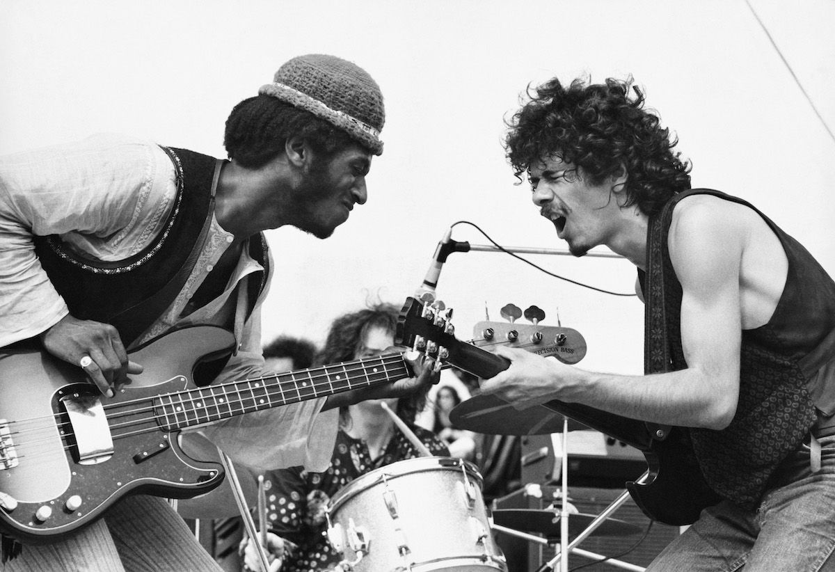 Rock musicians David Brown and Carlos Santana of Santana perform onstage during the Woodstock music festival in 1969