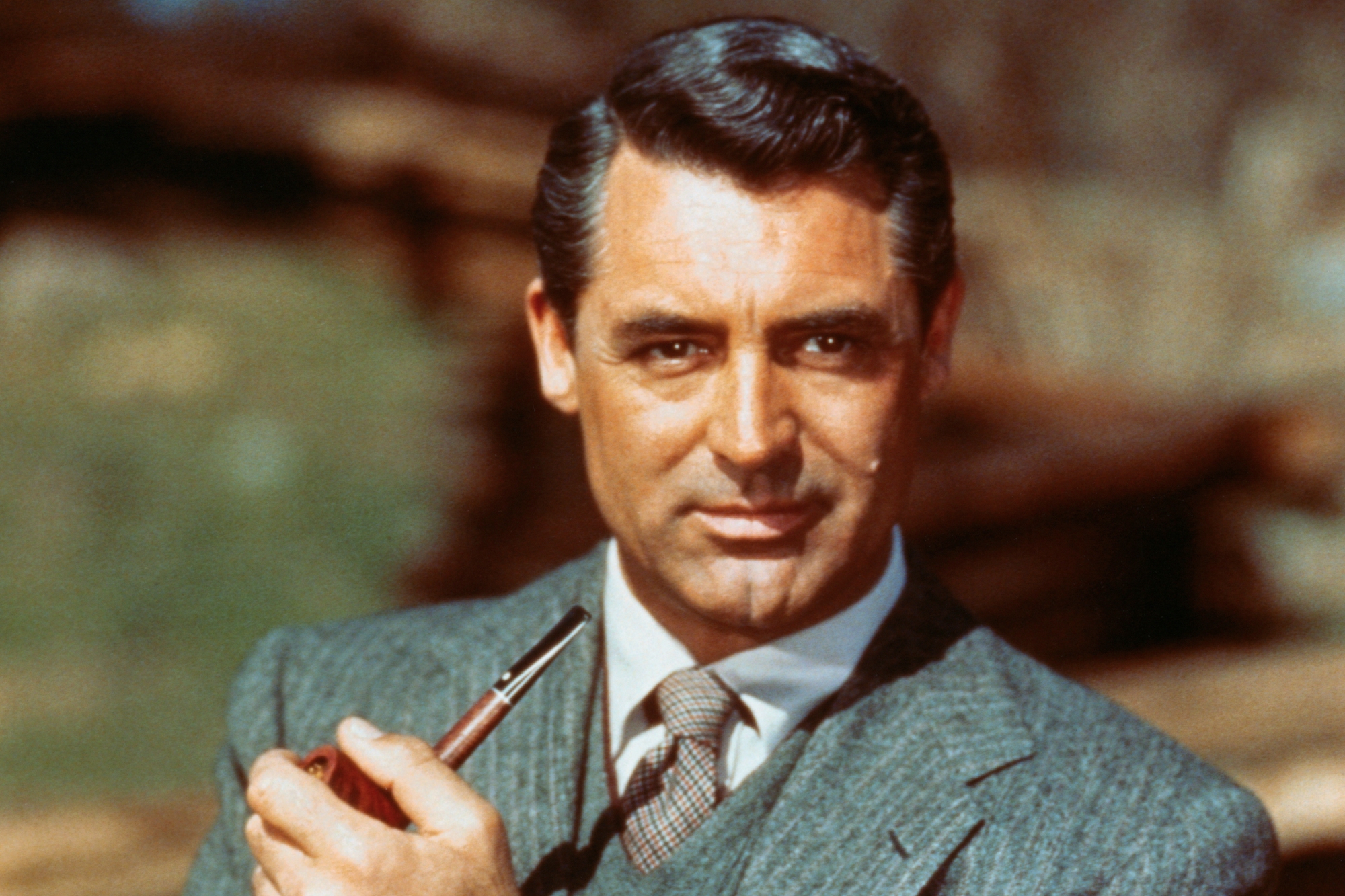 Cary Grant, who turned down 'My Fair Lady'. He's wearing a grey suit with a slight smile, holding a pipe.