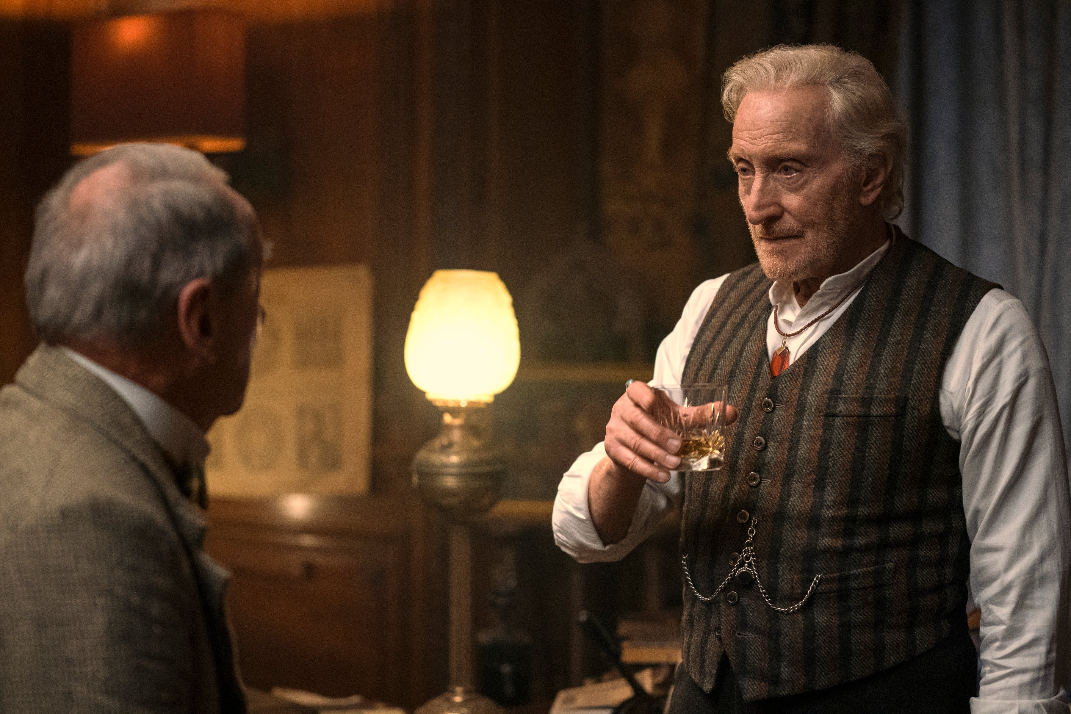 Charles Dance as Sir Roderick Burgess in 'The Sandman.' He's speaking to another man and holding a drink.