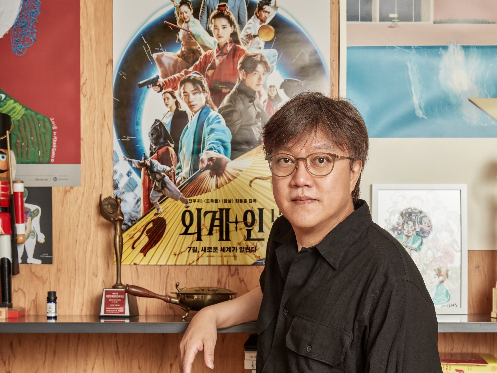 South Korean director, Choi Dong-hoon stands in front of the 'Alienoid' poster. 