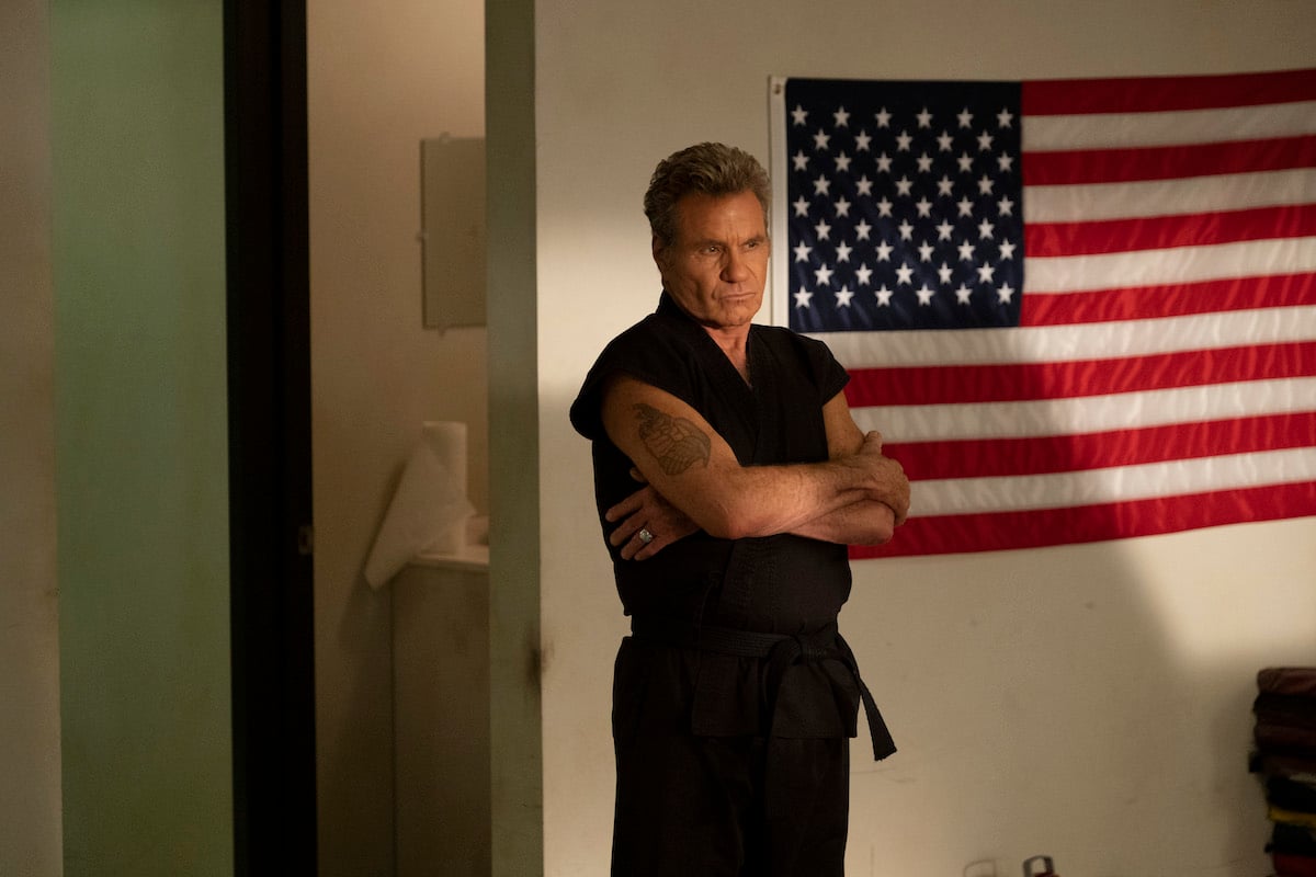 'Cobra Kai': Martin Kove as John Kreese stands with his arms folded in front of an American flag