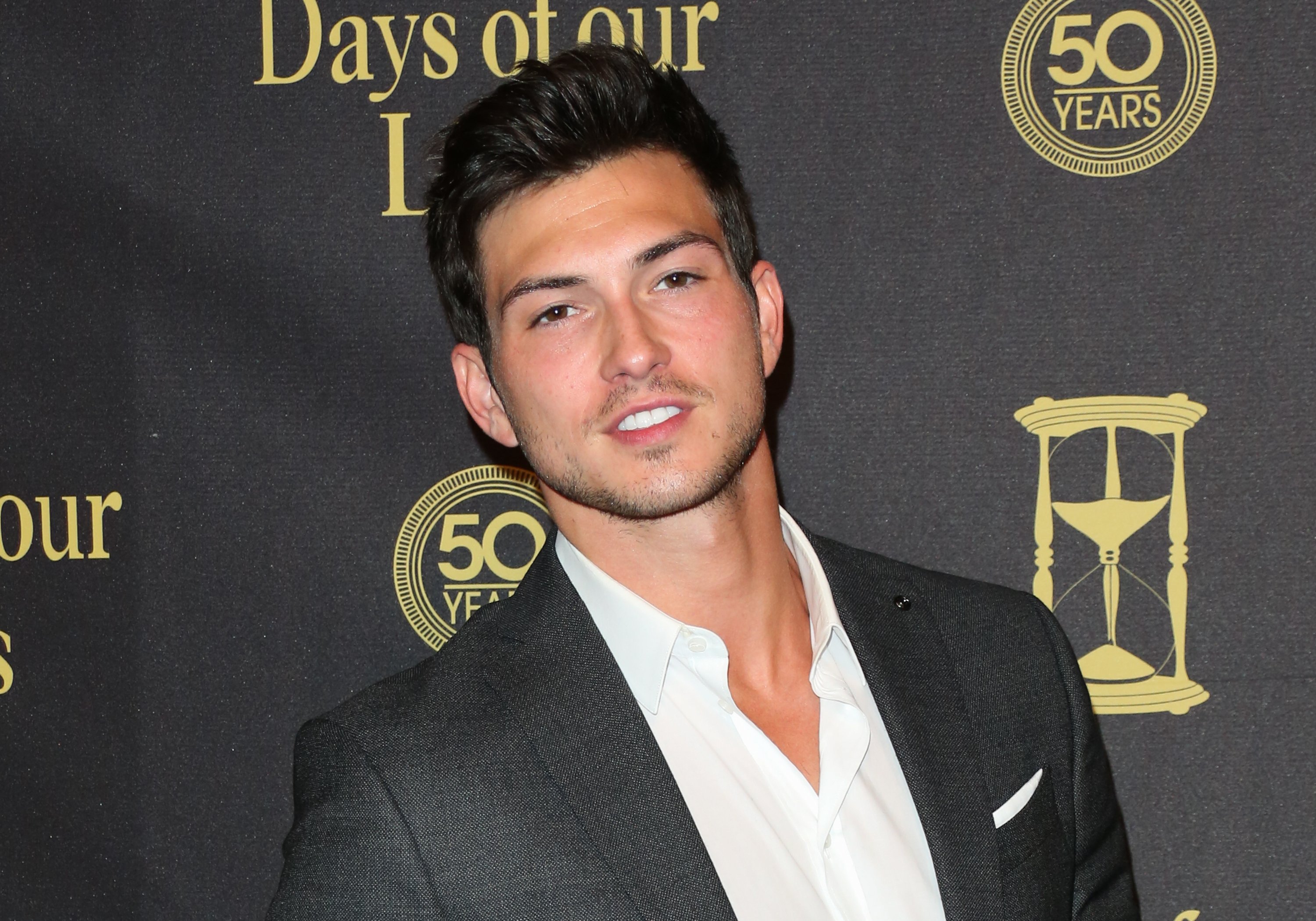 Actor Robert Scott Davis, who plays Alexander on 'Days of Our Lives,’ poses in a gray suit and white shirt.
