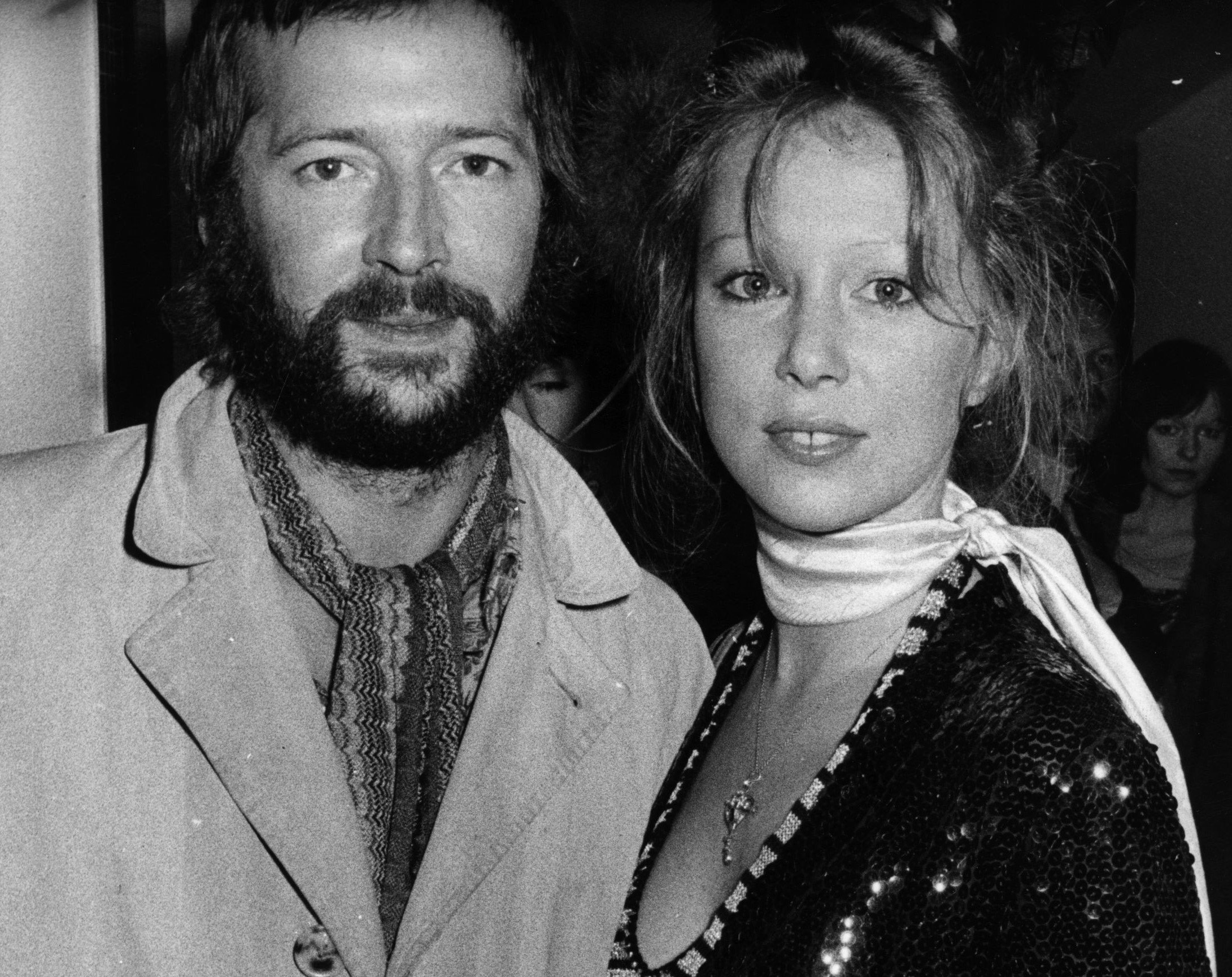A black and white picture of Eric Clapton and Pattie Boyd both wearing scarves around their necks.