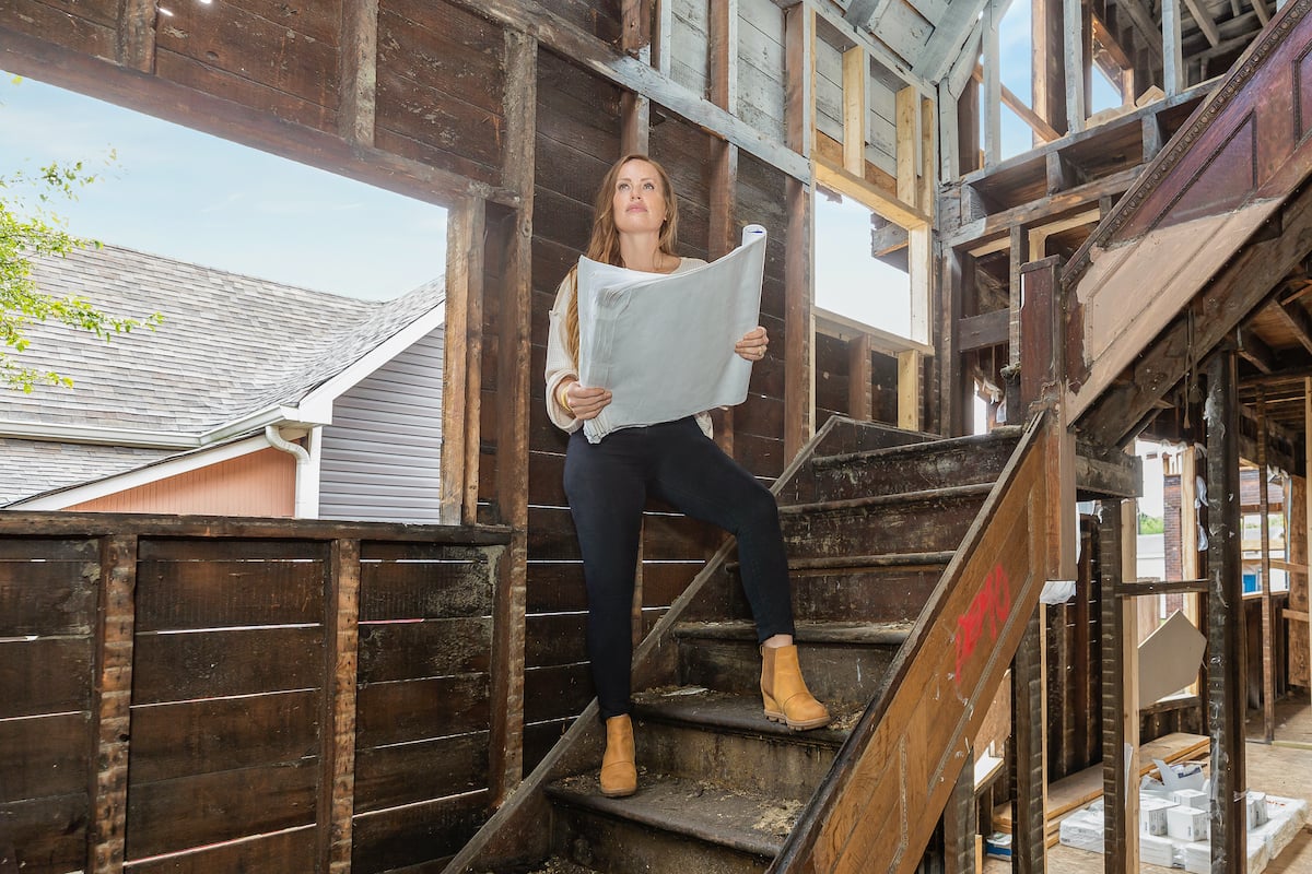Mina Starsiak Hawk standing on stairs and looking at plans in 'Good Bones: Risky Business'