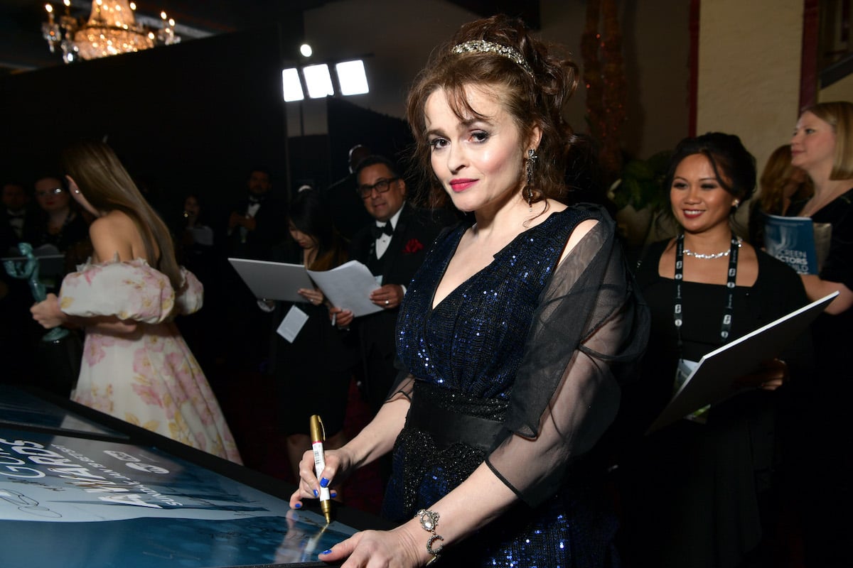 Helena Bonham Carter smiling slightly, signing a photo