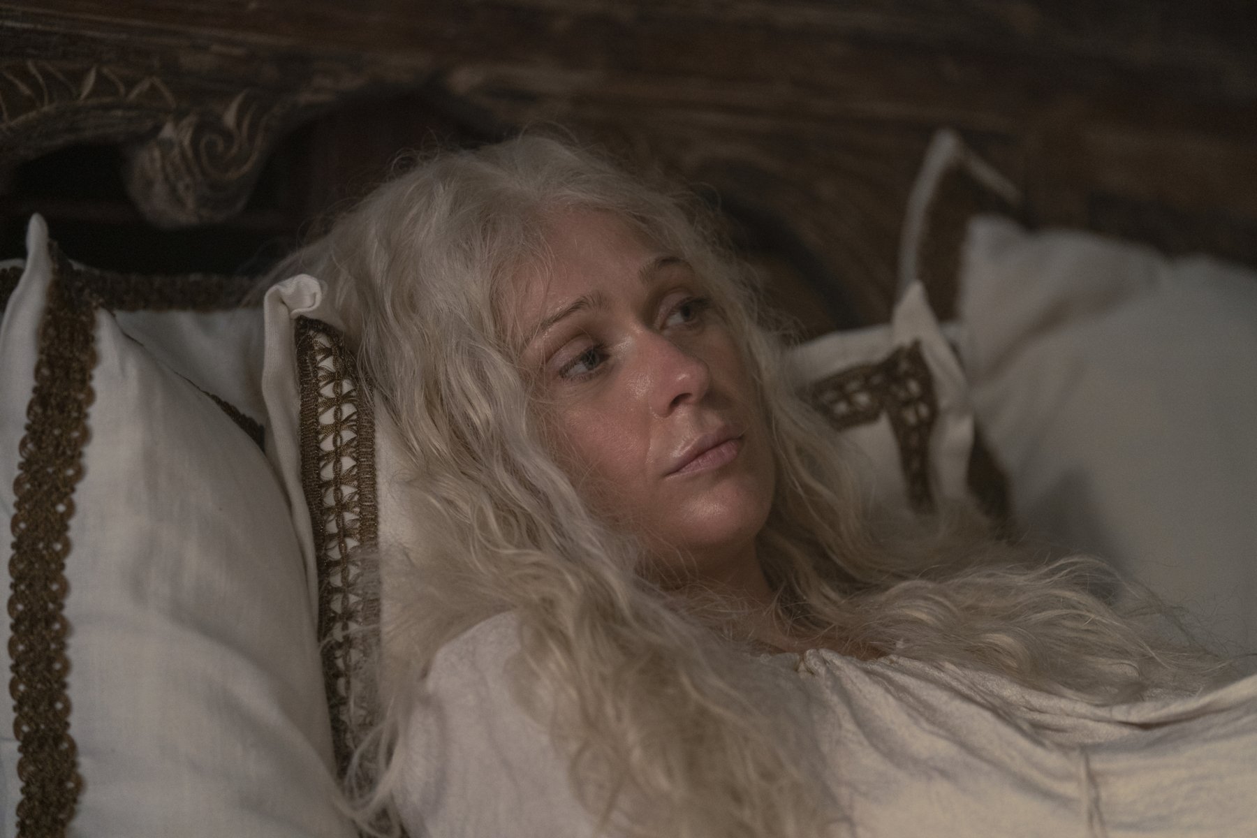 Sian Brooke as Aemma Arryn in 'House of the Dragon,' which has a controversial birth scene in its premire. She's lying on a bed with her hair messy and face sweaty.