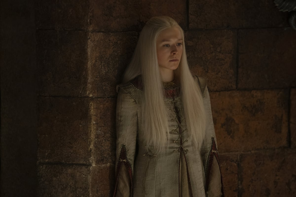 Emma D'Arcy as Rhaenyra in House of the Dragon. Rhaenyra has long blonde hair and wears a grey dress.