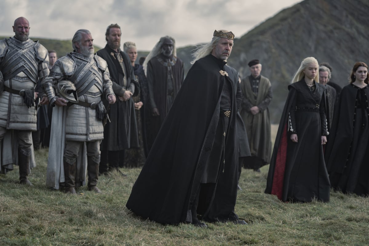 Paddy Considine, Rhys Ifans, Eve Best, Steve Toussaint, Milly Alcock, and Emily Carey in House of the Dragon. The characters stand outside for Queen Aemma and Prince Baelon's funeral.