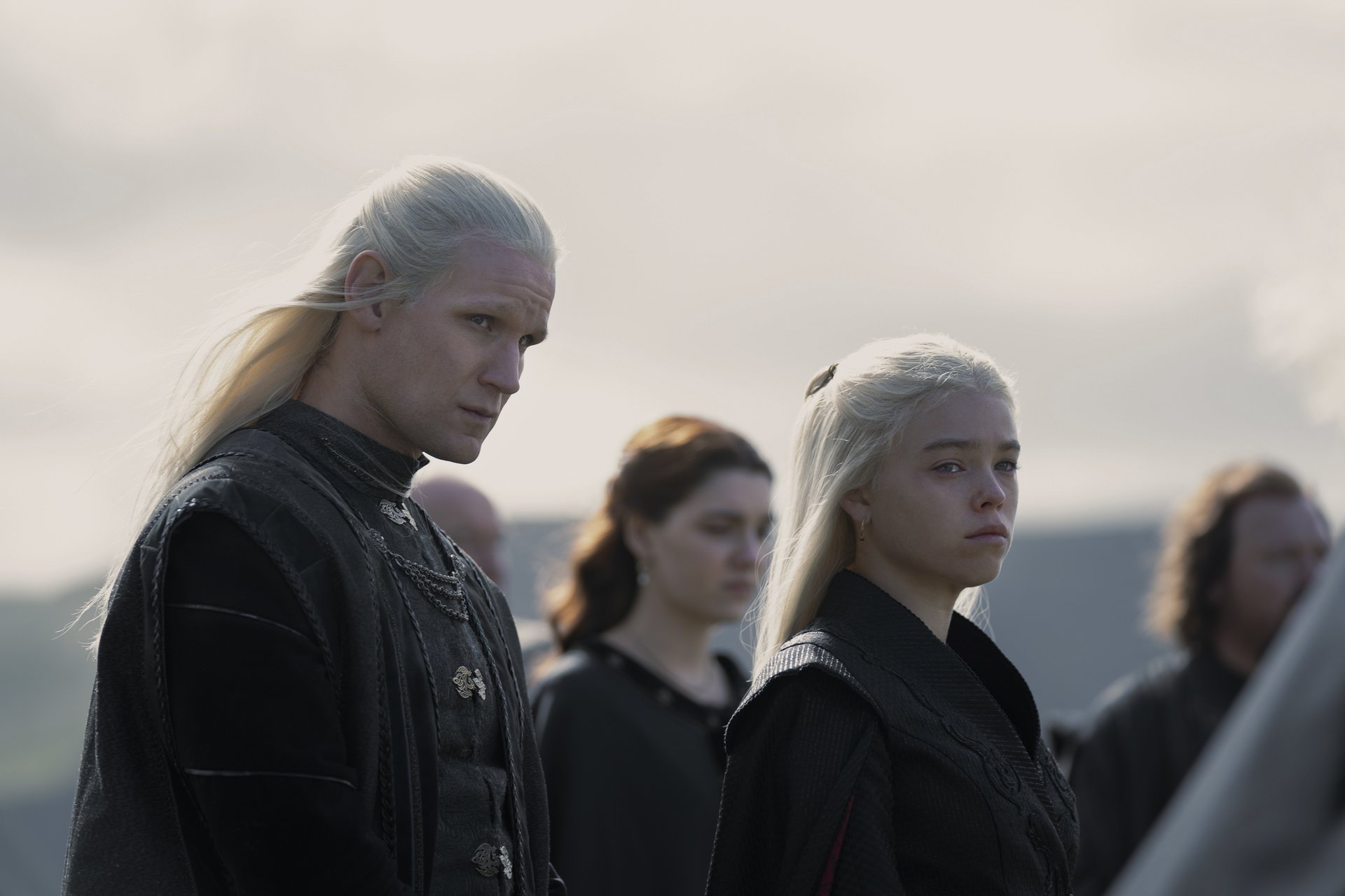 Matt Smith and Milly Alcock as Rhaenyra and Daemon Targaryen in 'House of the Dragon,' which is based on events outlined in George R.R. Martin's book, 'Fire & Blood.' They're both staring toward the camera, and Rhaenyra looks unhappy.