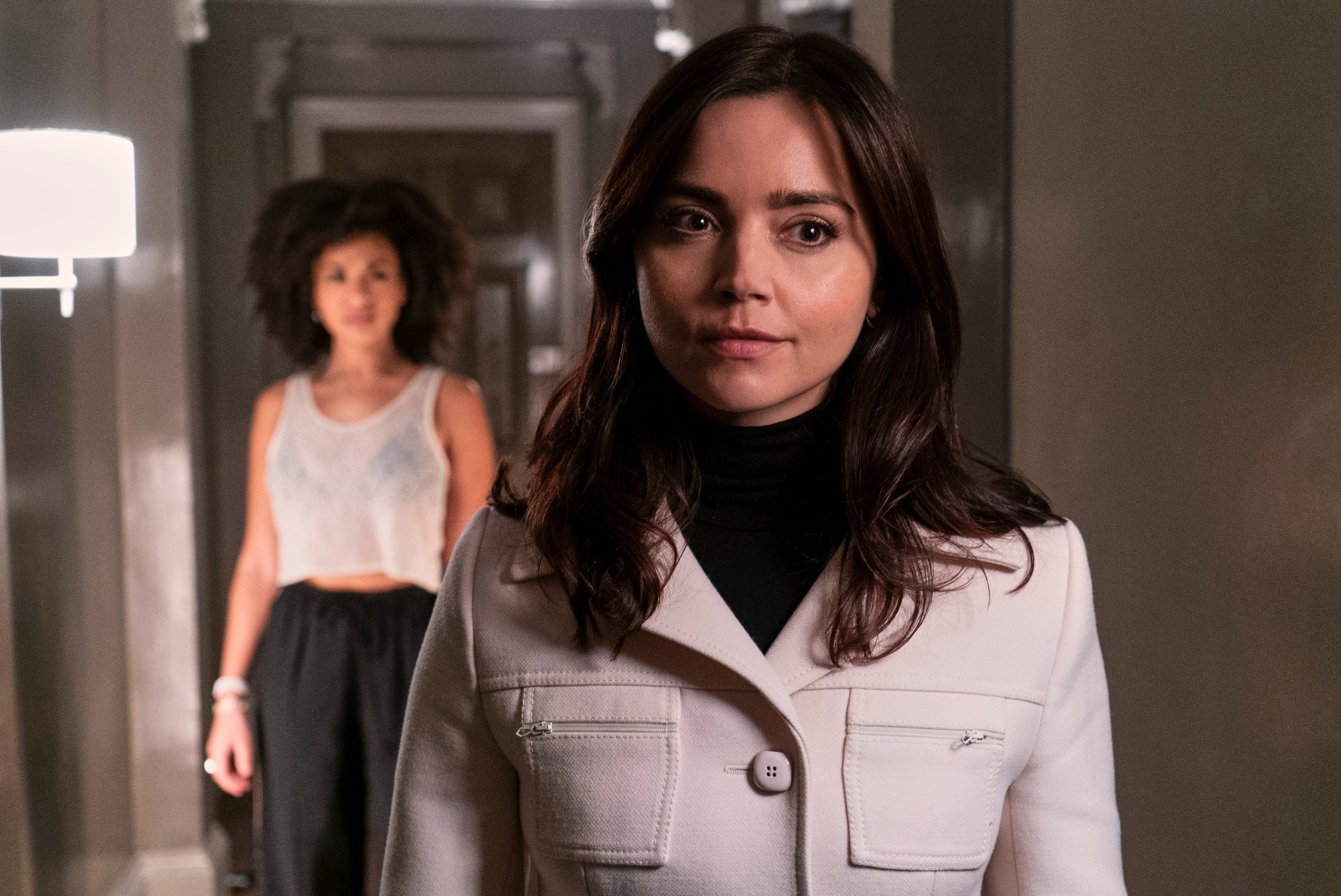 Jenna Coleman as Johanna Constantine in the cast of 'The Sandman.' She's wearing a white coat, and another woman is behind her.