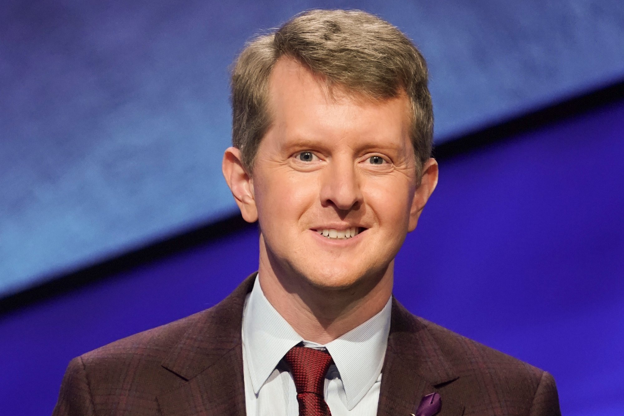 'Jeopardy!' host and champion Ken Jennings smiling wearing a suit and tie
