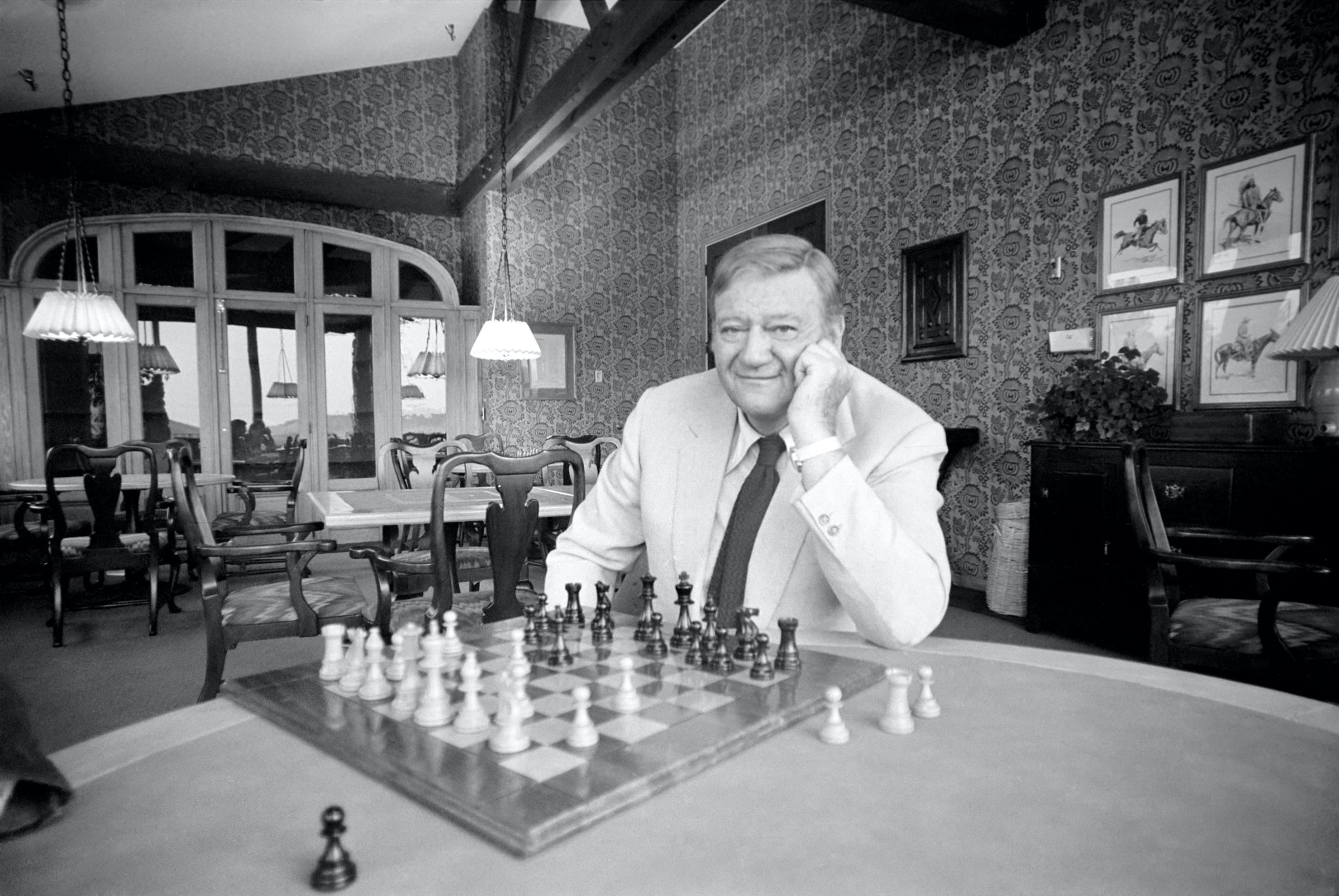 Actor John Wayne at his home in Texas playing chess