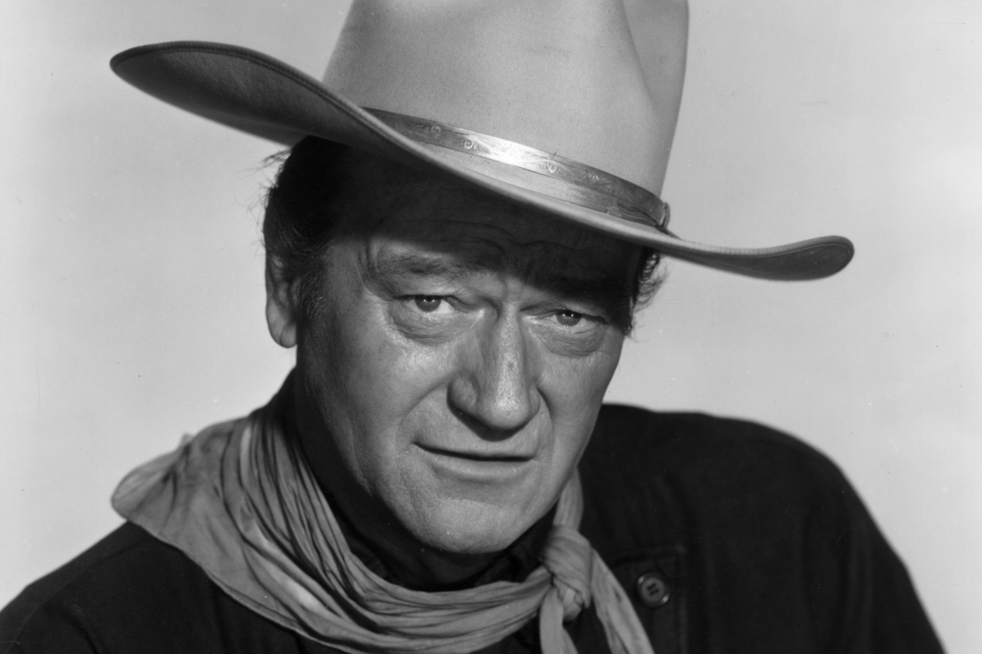 John Wayne, whose real name was Marion Michael Morrison, looking into the camera while wearing a cowboy hat