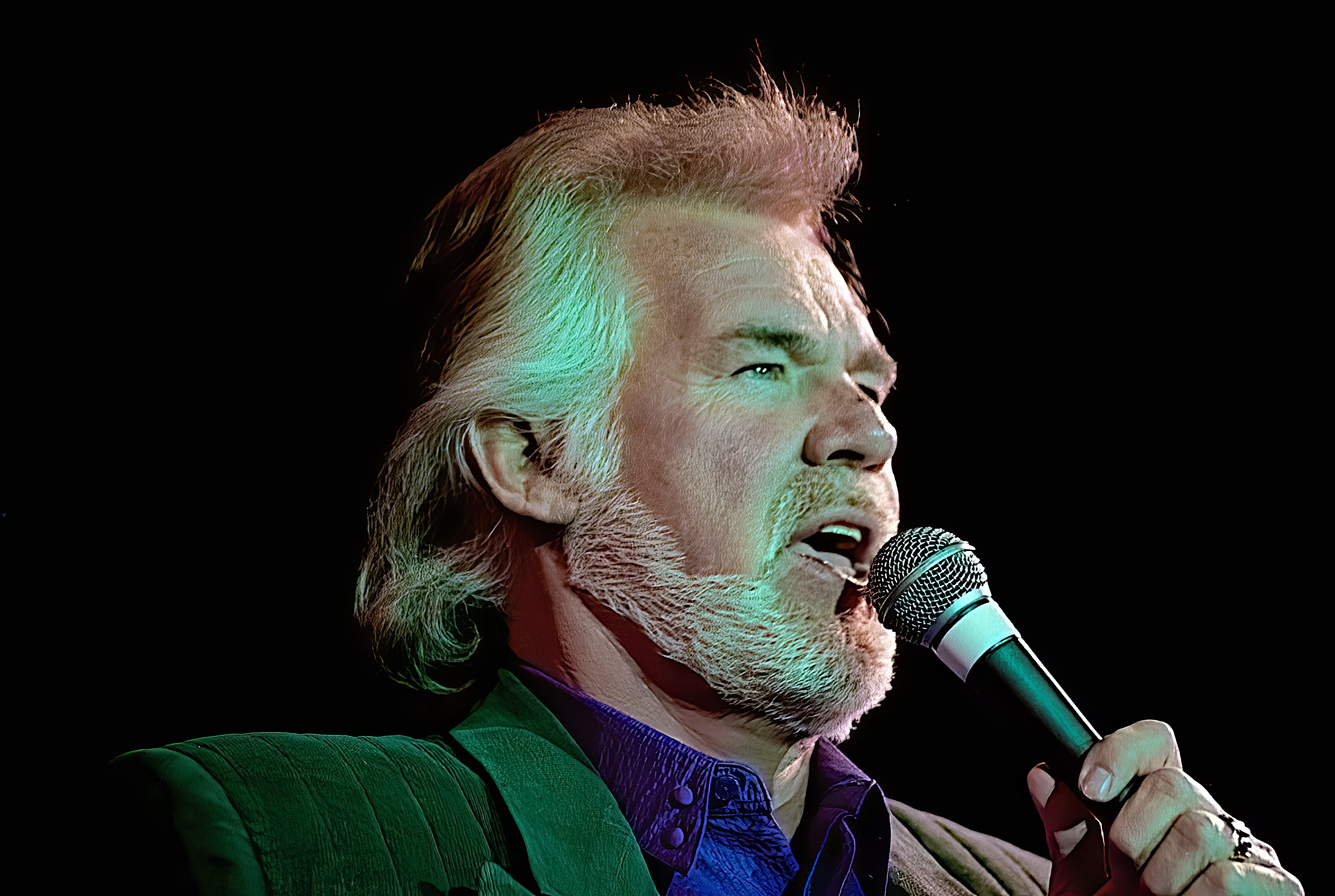 Kenny Rogers holds a microphone while singing.