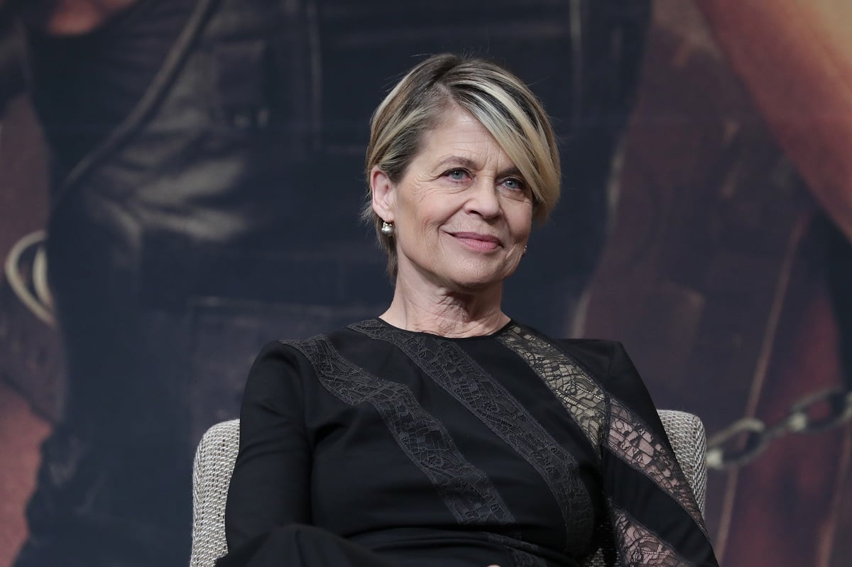 Linda Hamilton smirking while wearing a black dress.