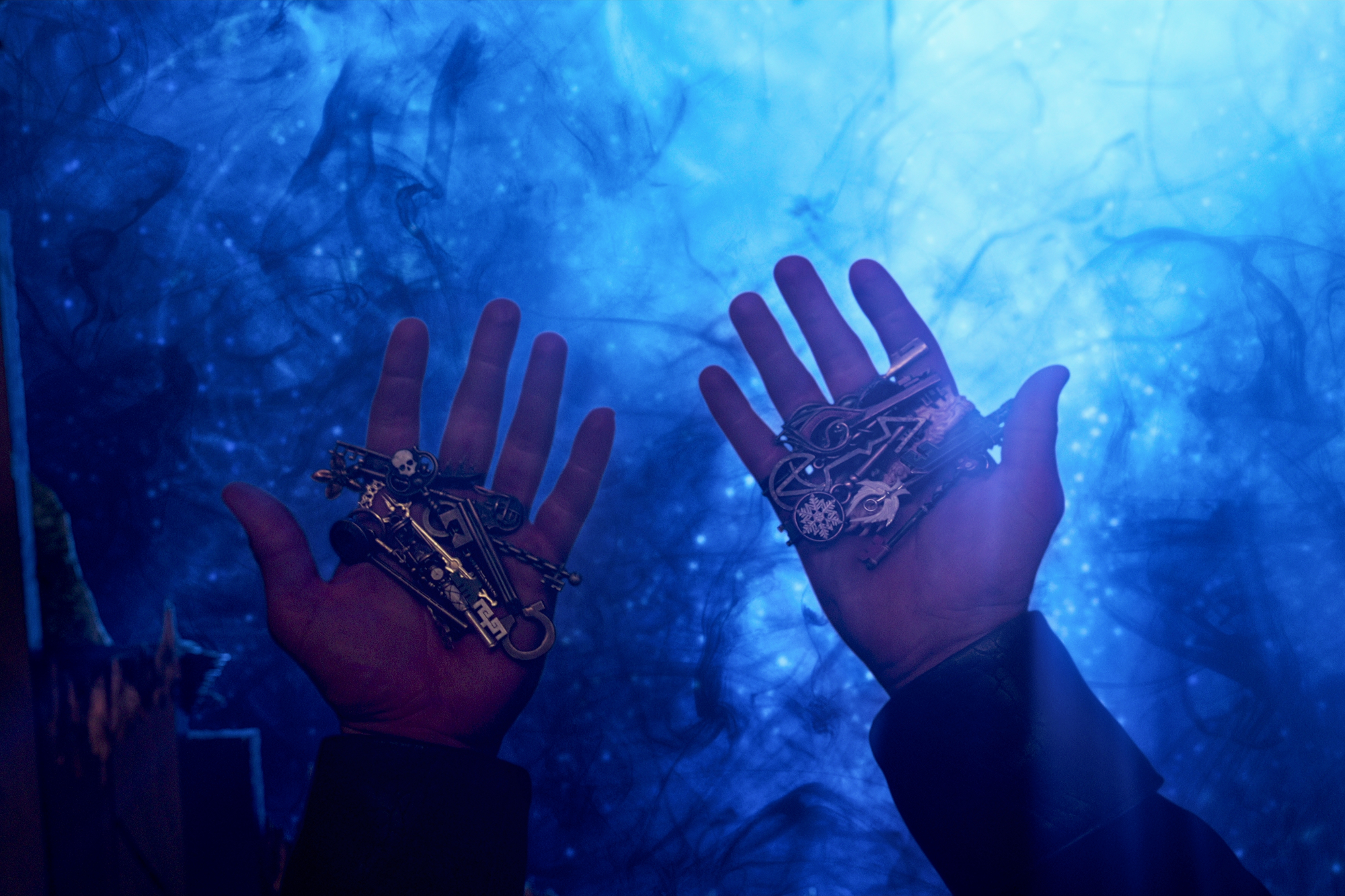 All of the Keys, including the Echo Key, in 'Locke & Key' Season 3. Someone is holding them in their hands, and there's blue light in the background.