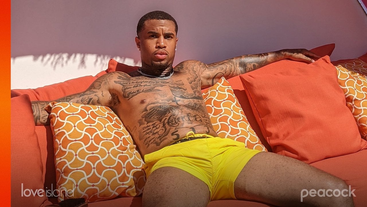 Jeff Christian Jr. sits on an orange couch and pillows outside on 'Love Island USA'