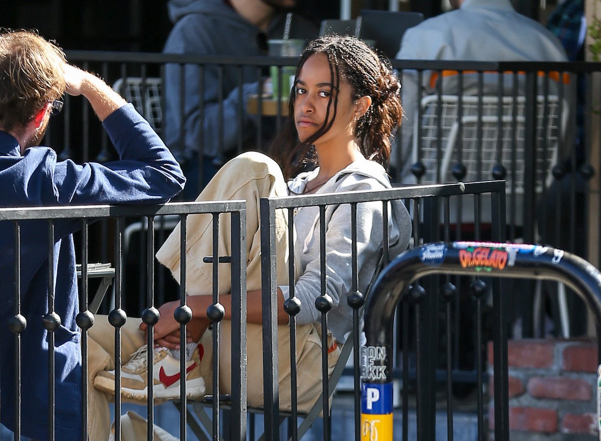Malia Obama, age 24, sitting outside and looking at the camera