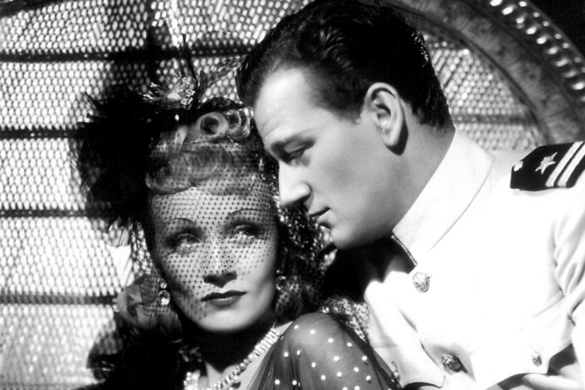 Marlene Dietrich and John Wayne looking in one another's eyes on the set of 'Seven Sinners'