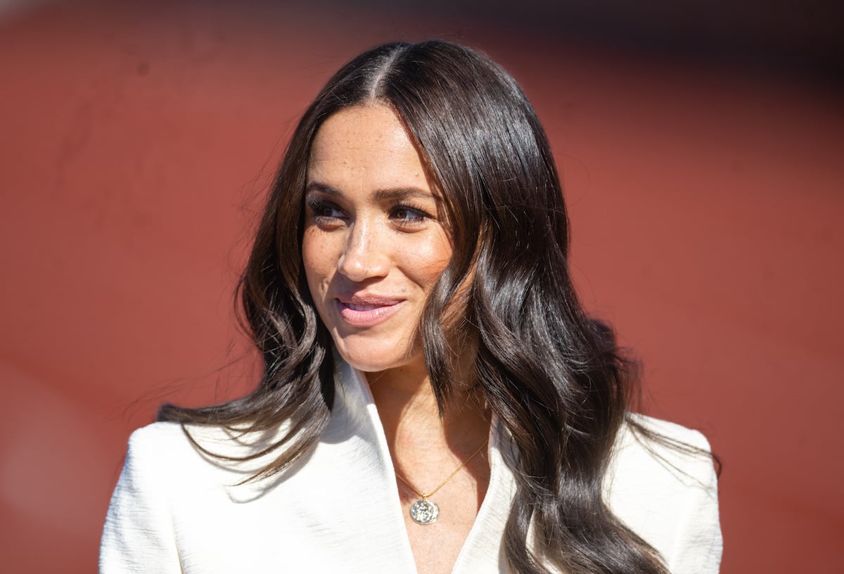 Meghan Markle, who an author described as 'uncensored and unfilted' on her 'Archetypes' podcast premiere on Spotify, smiles and looks on