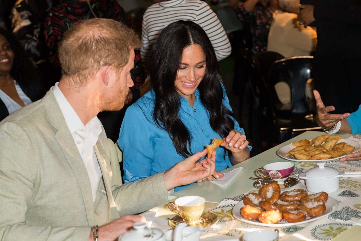 Meghan Markle and Prince Harry try some food during their visit to South Africa